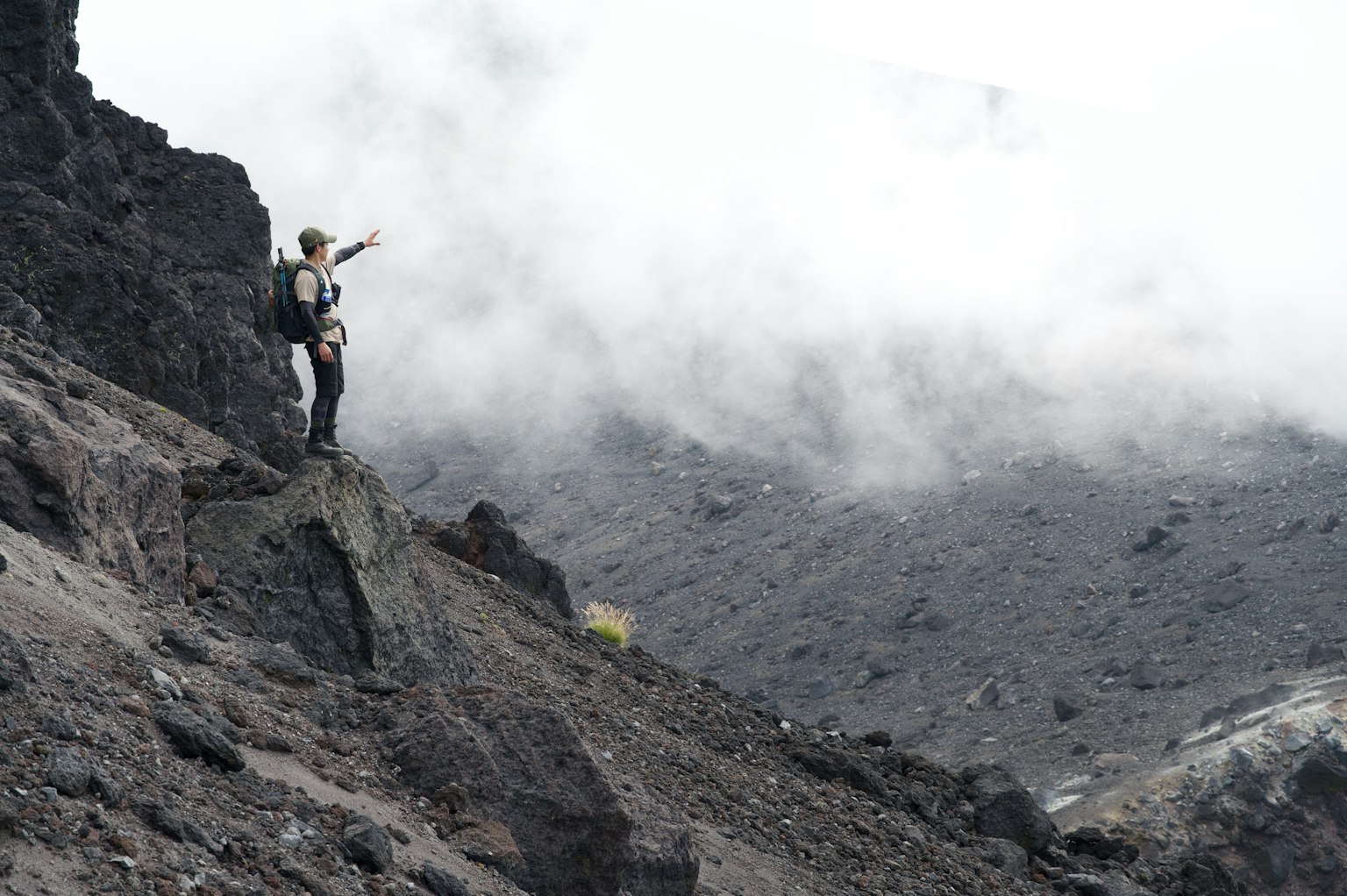 攀登者站在被云雾和岩石地形环绕的火山景观中