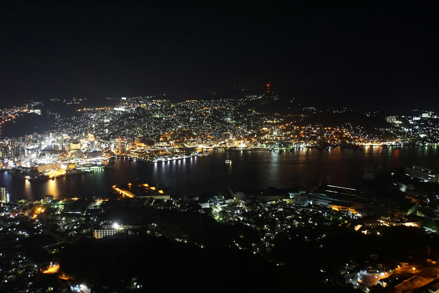 Vista panoramica della città di Nagasaki di notte con luci scintillanti e porto