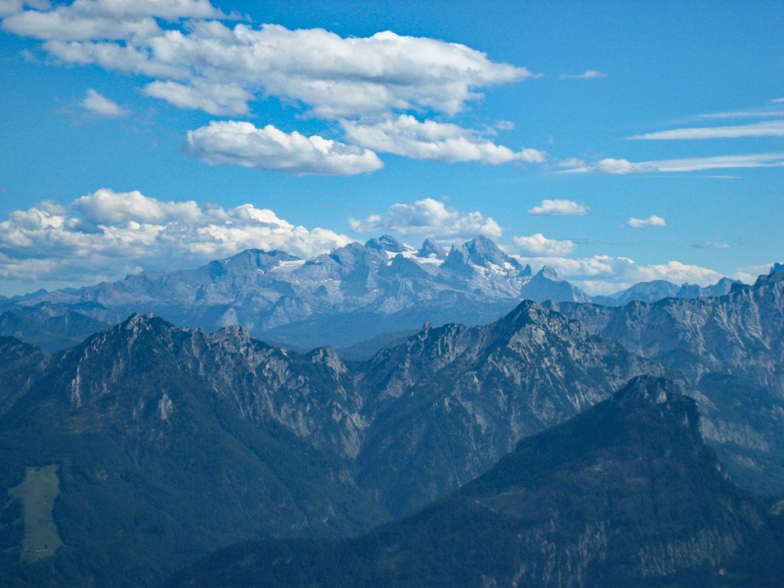 Paysage montagneux sous un ciel bleu avec des nuages blancs
