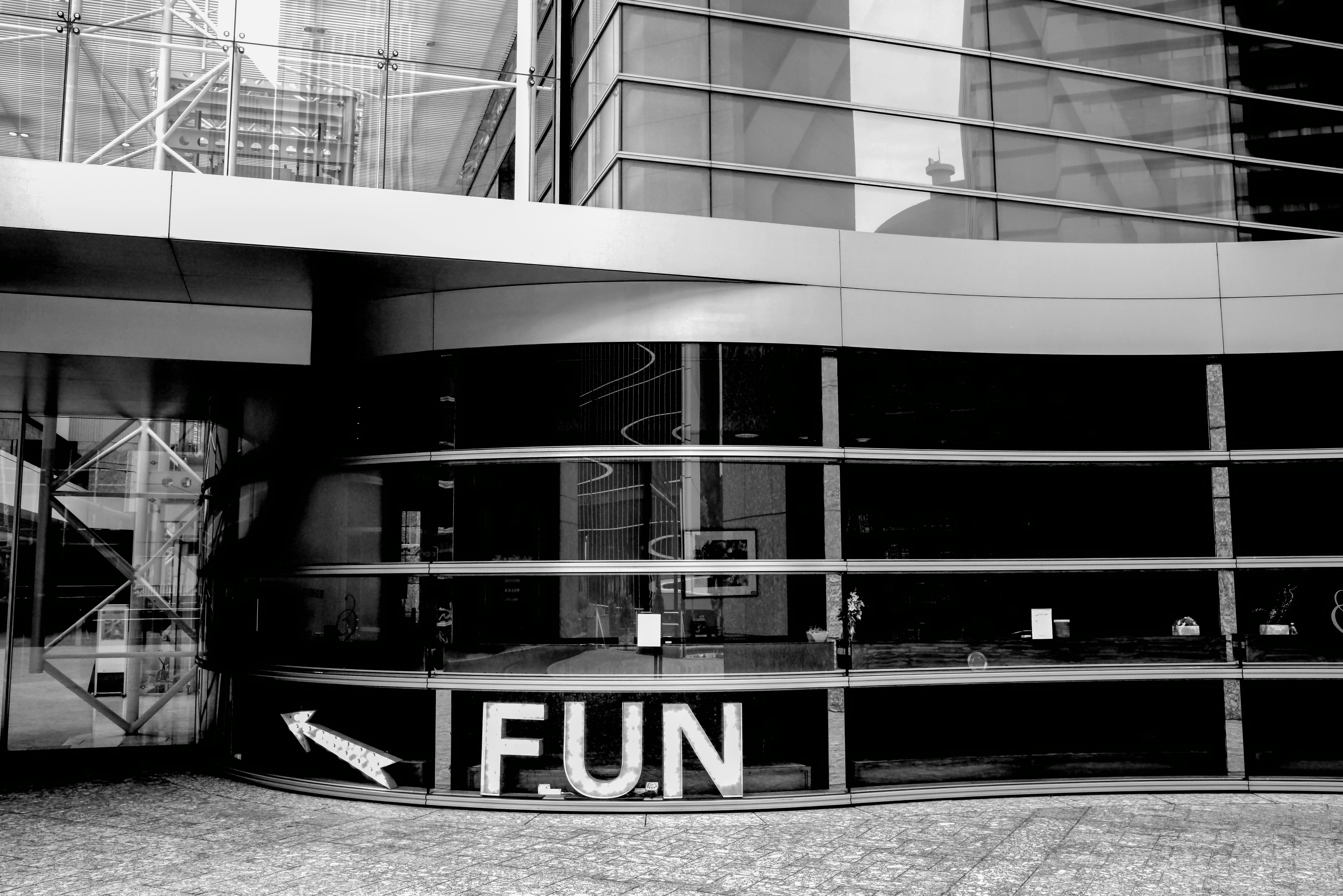 outdoor walkway with a glass building and a “FUN” sign