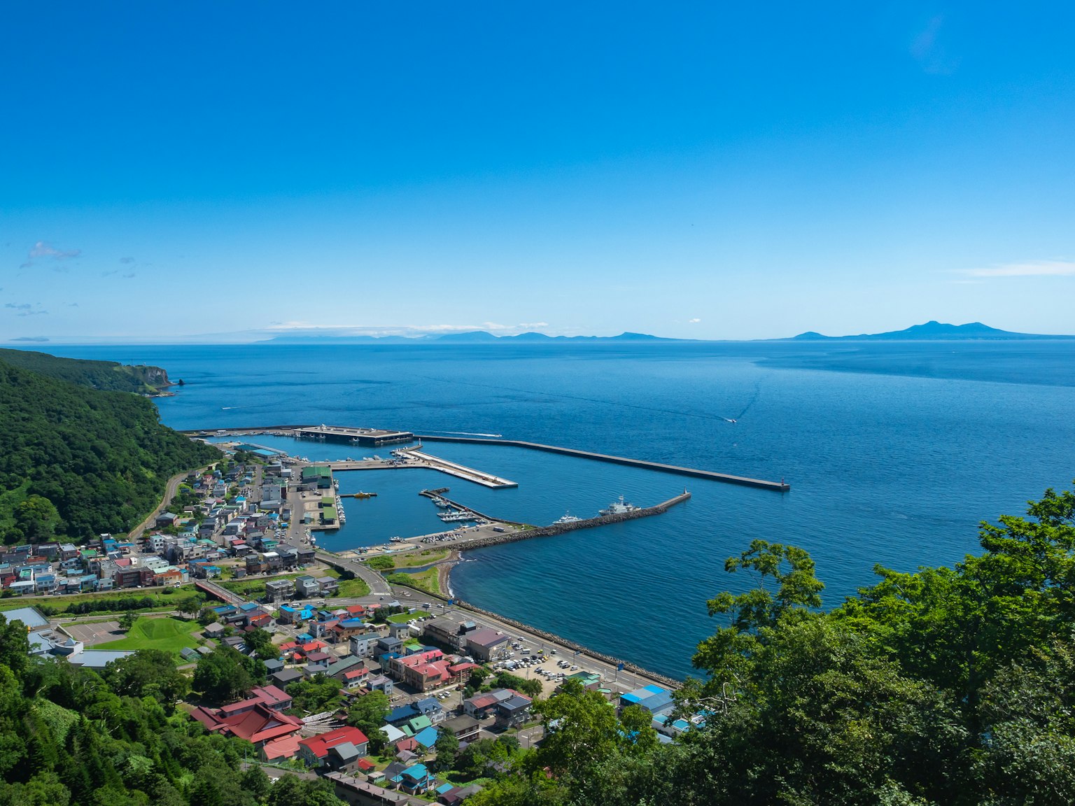 Vista escénica de un pueblo costero con océano azul y puerto rodeado de montañas