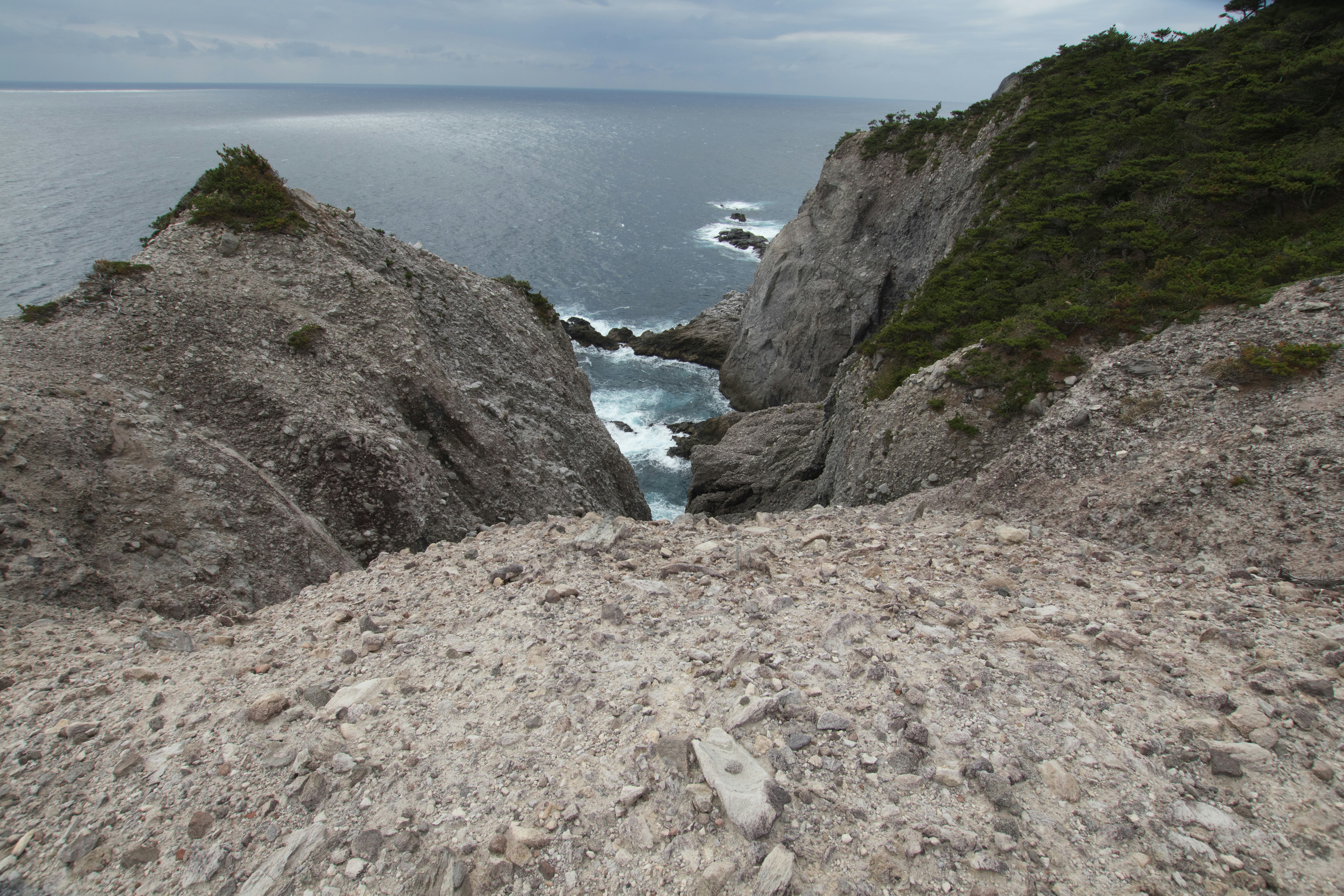 Felsige Klippenlandschaft mit Blick auf den Ozean und grüner Vegetation