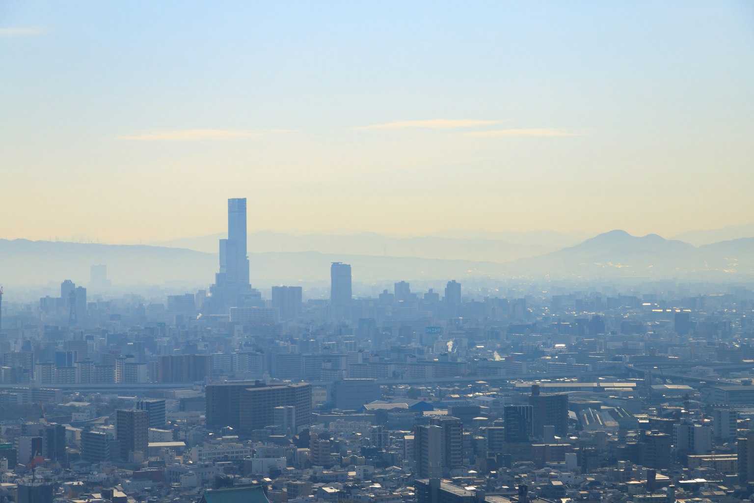 Pemandangan cakrawala Tokyo dengan gedung pencakar langit dan pegunungan jauh di bawah langit berkabut