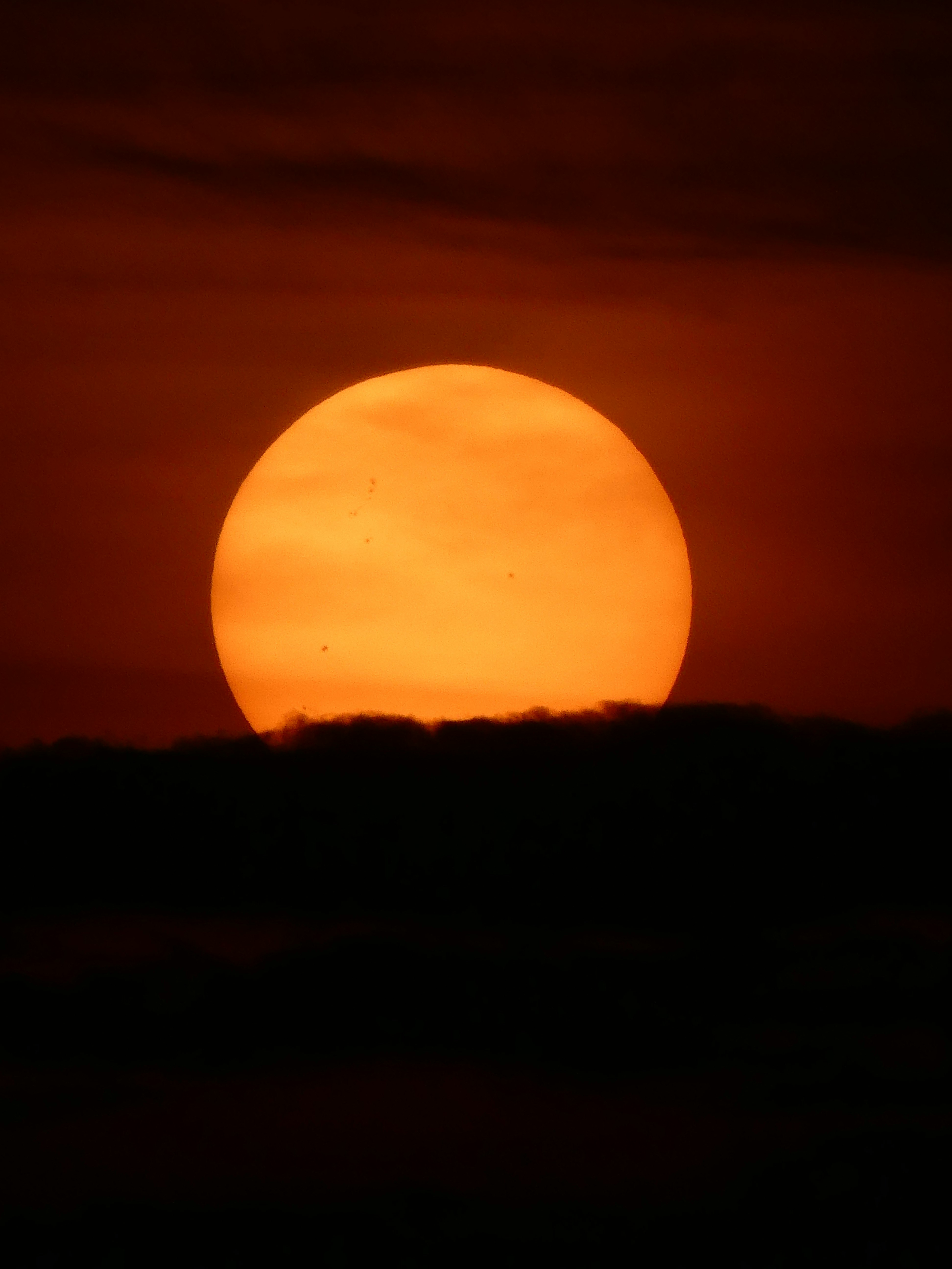 夕焼けの地平線に浮かぶ大きなオレンジ色の太陽