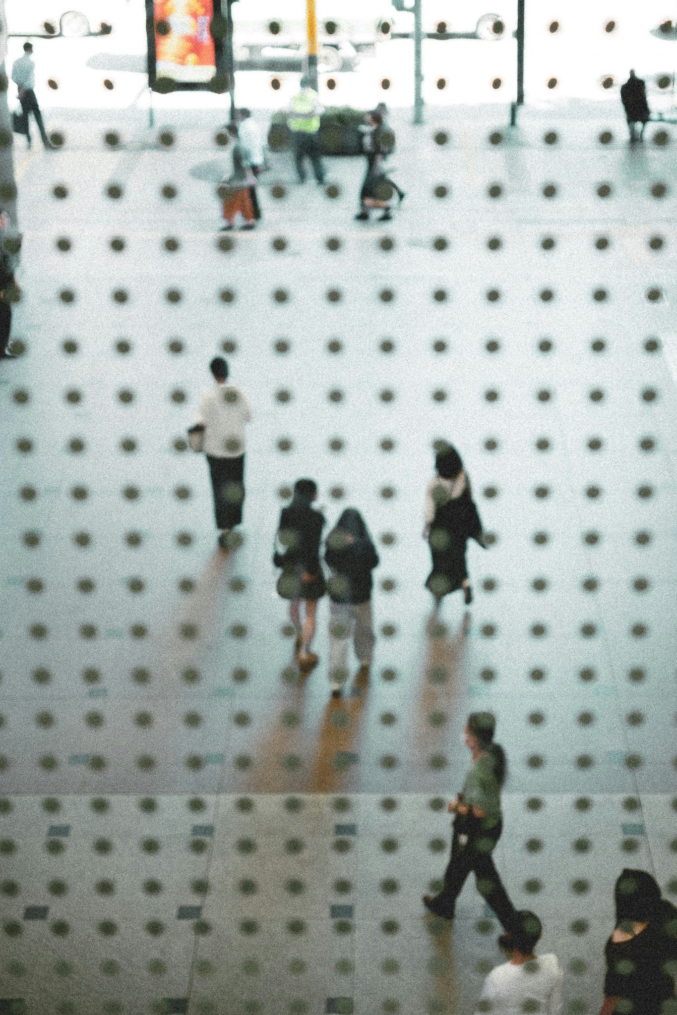 白い壁に穴あきボードが並ぶ展示空間で人が歩く