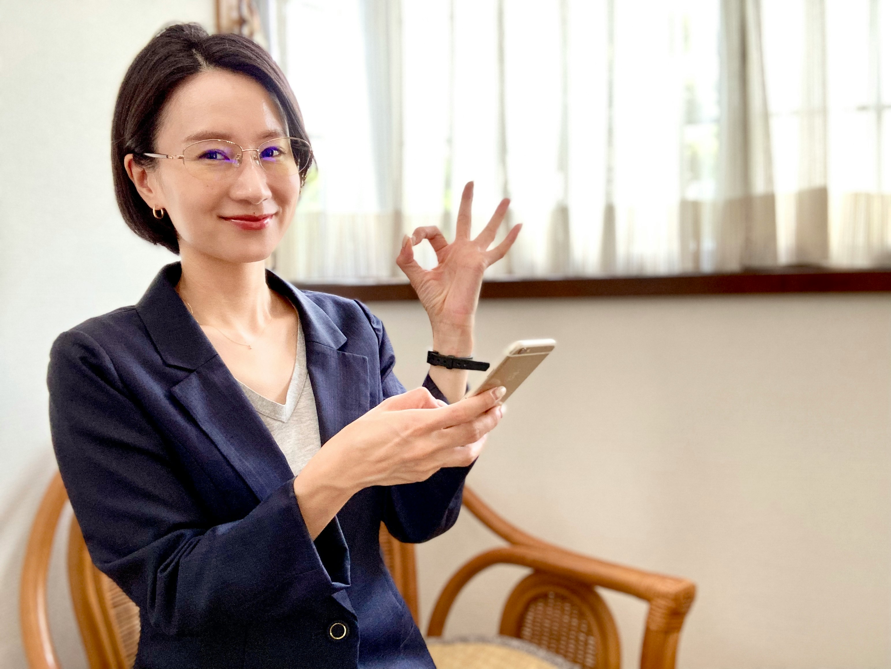 Mujer sonriente con un teléfono inteligente saludando en interiores
