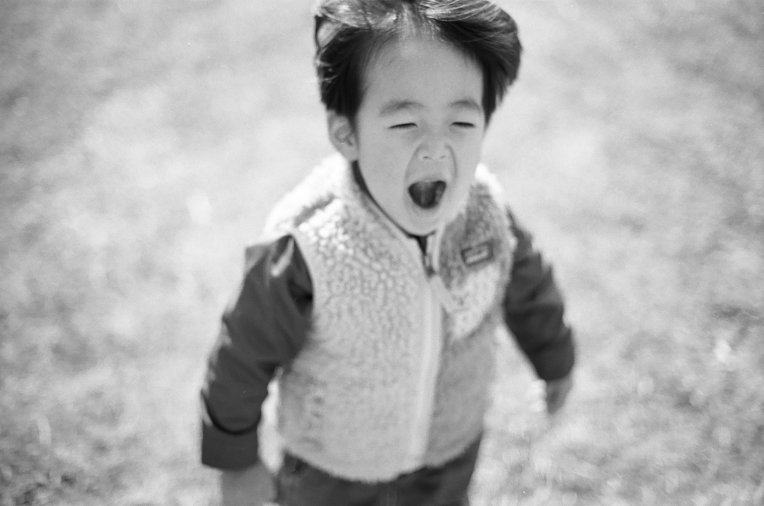 Black and white photo of a child laughing outdoors