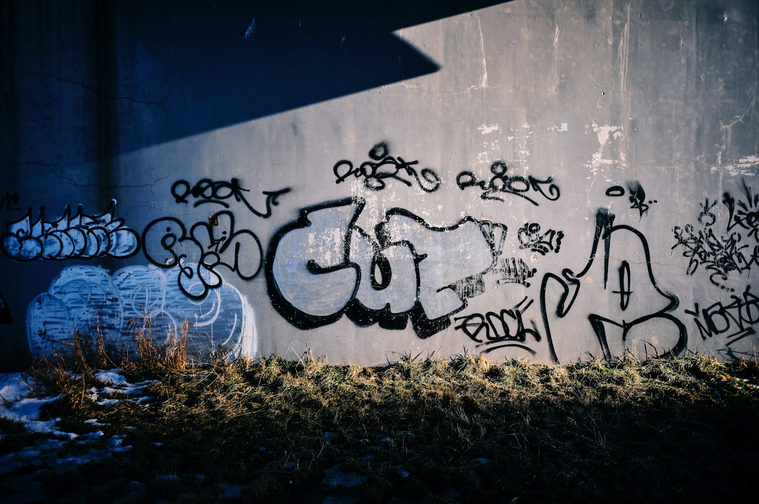 Diverse graffiti art on a dark wall with a shadow effect