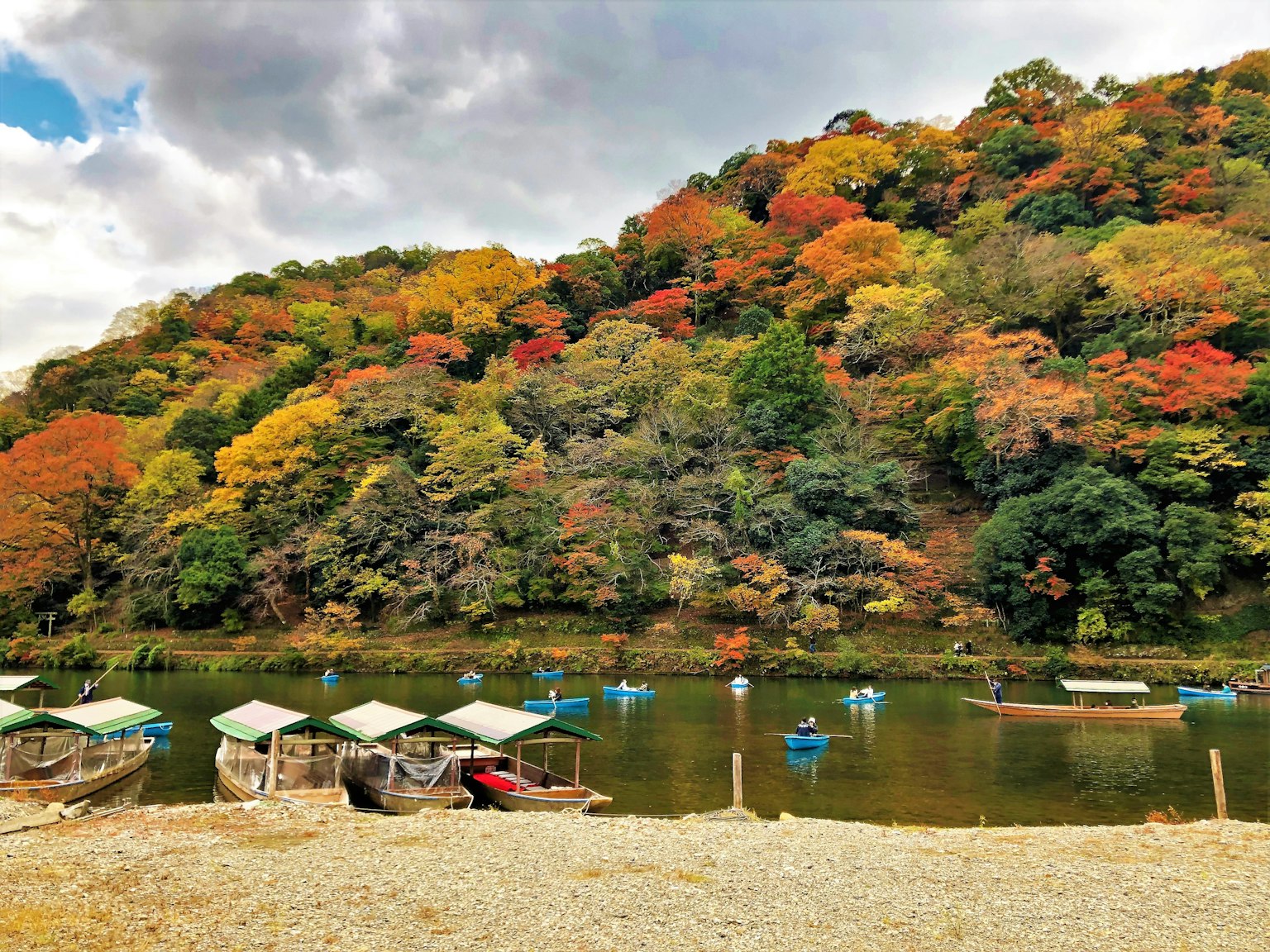 Paesaggio autunnale scenico con alberi colorati e piccole barche su un lago tranquillo