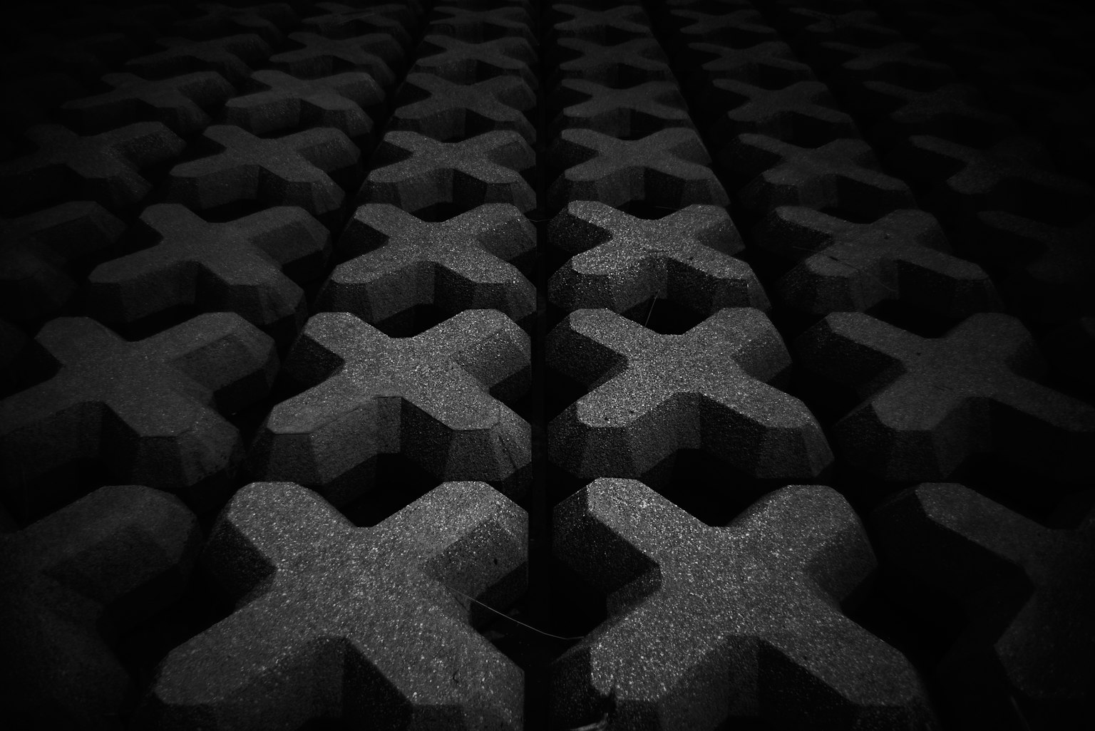 Patrón 3D de formas en X dispuestas sobre un fondo negro
