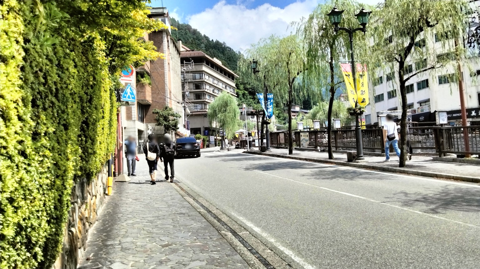 Street view with green foliage and buildings under a blue sky