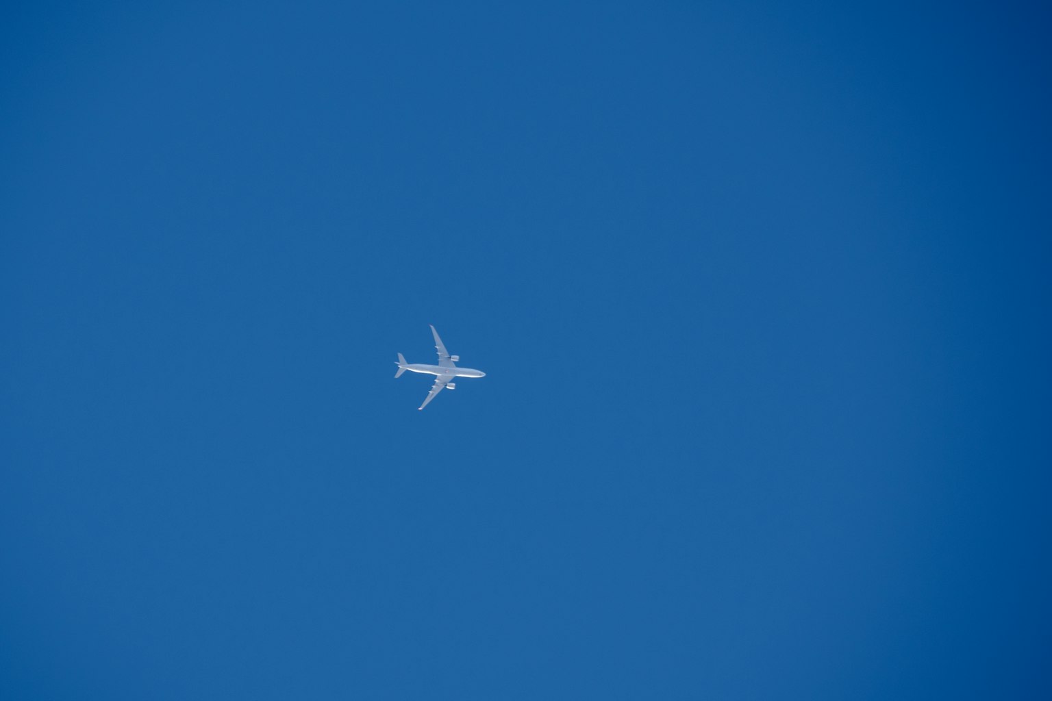 Sebuah pesawat putih terbang di langit biru