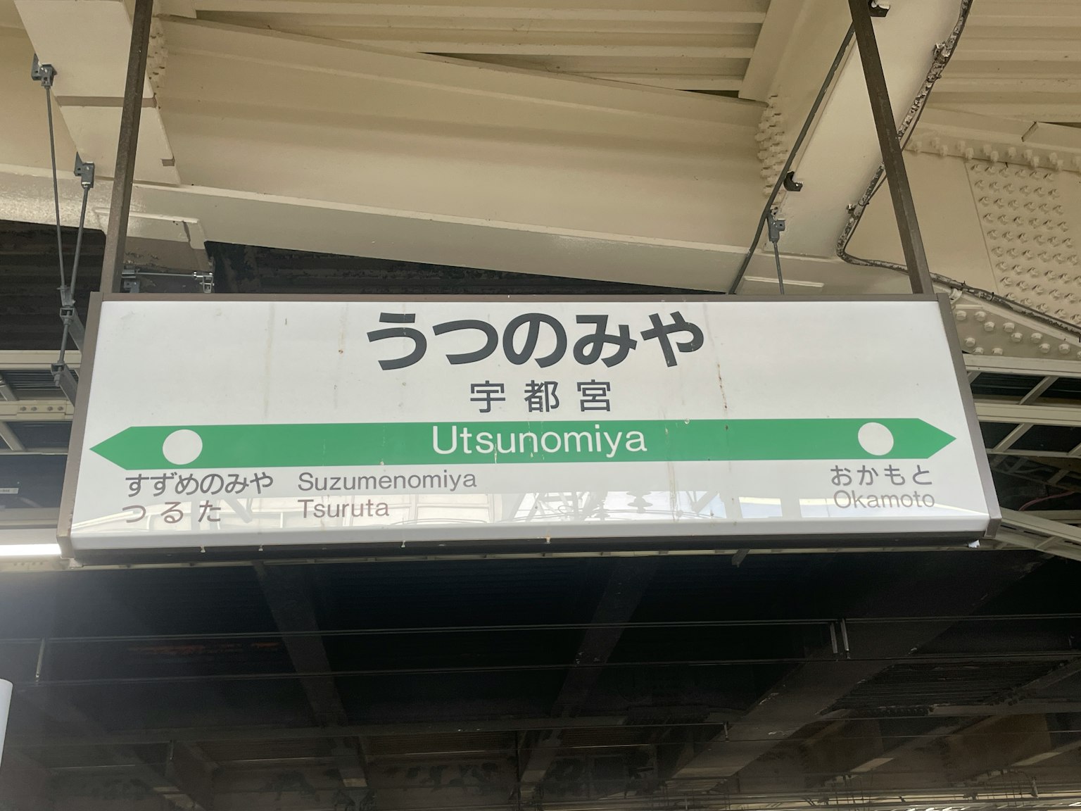 Gambar papan stasiun Utsunomiya menampilkan panah hijau dan teks dalam bahasa Jepang dan Inggris