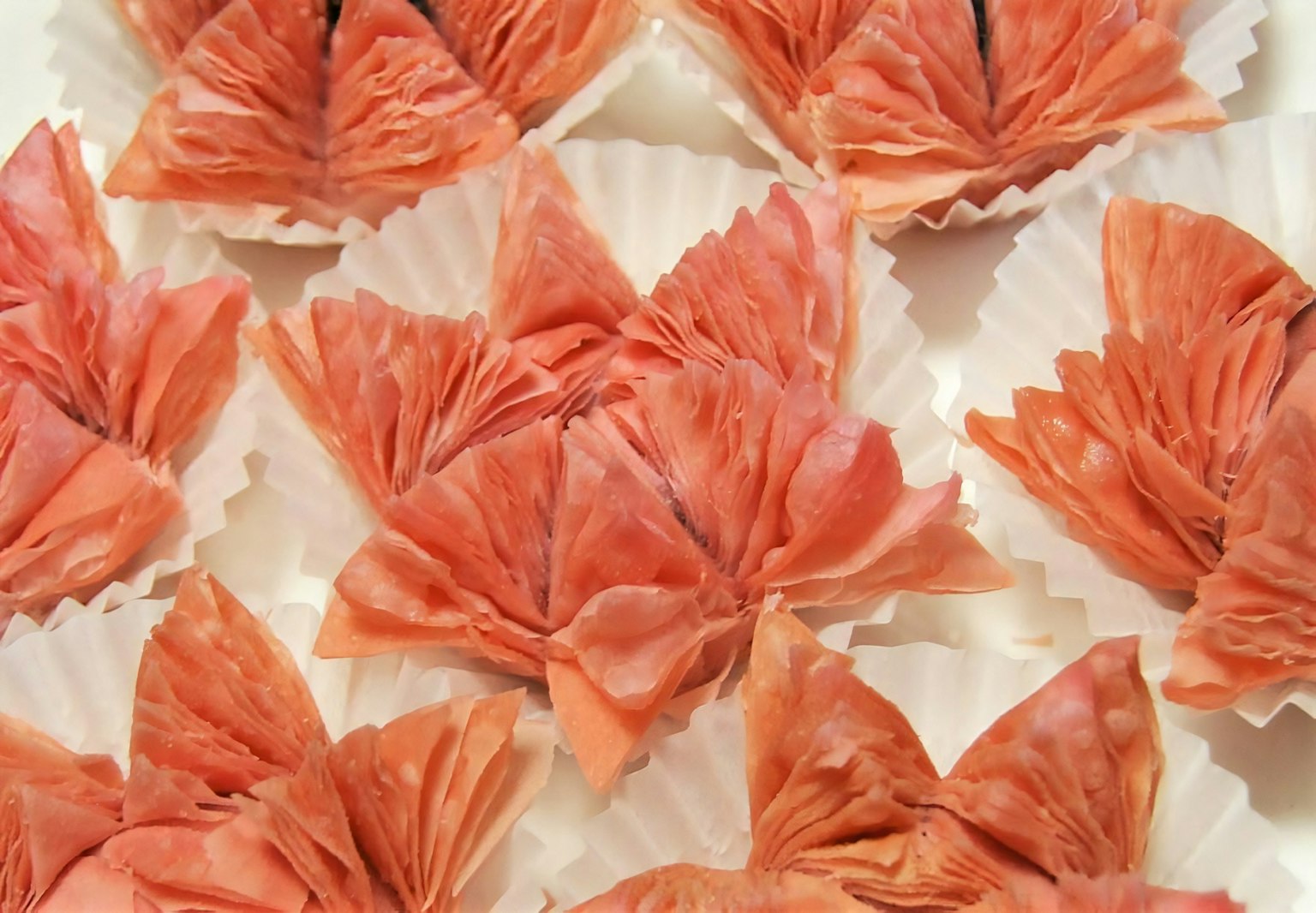 Dolci rosa delicati disposti a forma di petali su coppette bianche