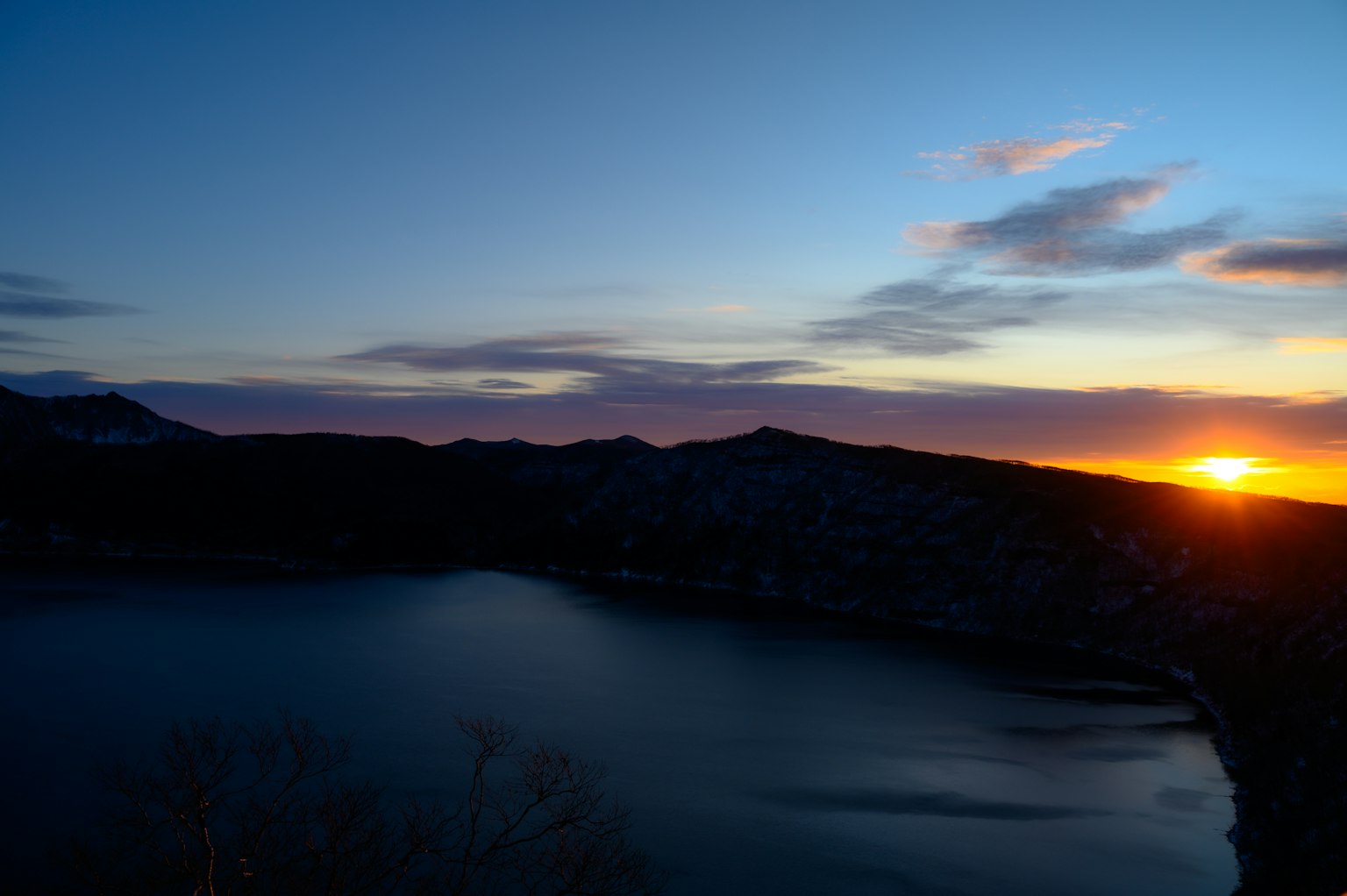 Stupendo tramonto su un lago tranquillo con montagne sullo sfondo