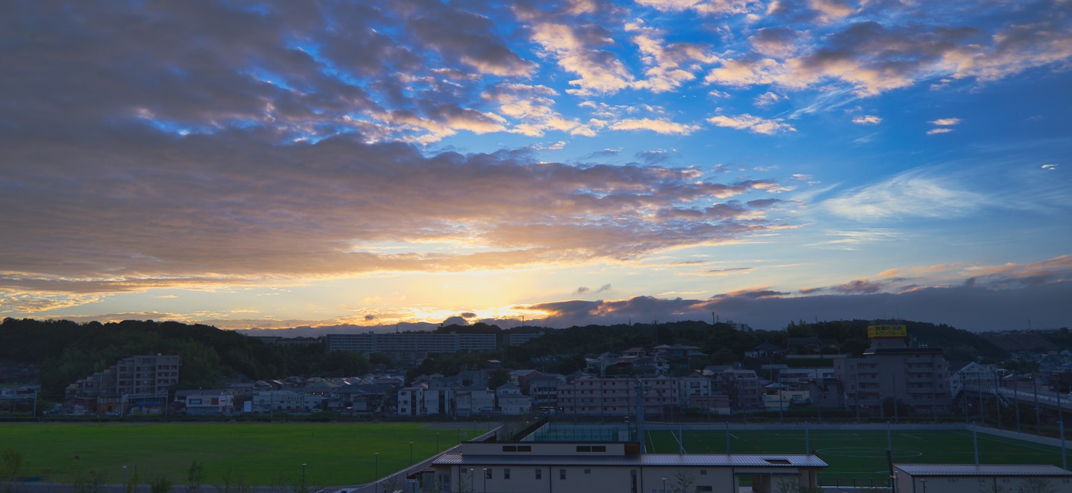 夕阳下的风景蓝天和云朵绿色草地和建筑物可见