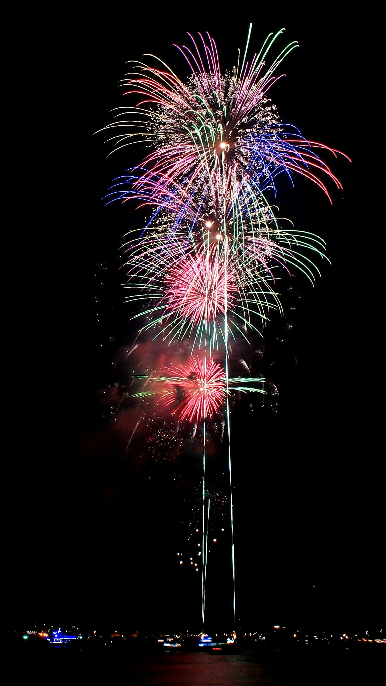 Colorful fireworks display in the night sky with red, blue, and white bursts
