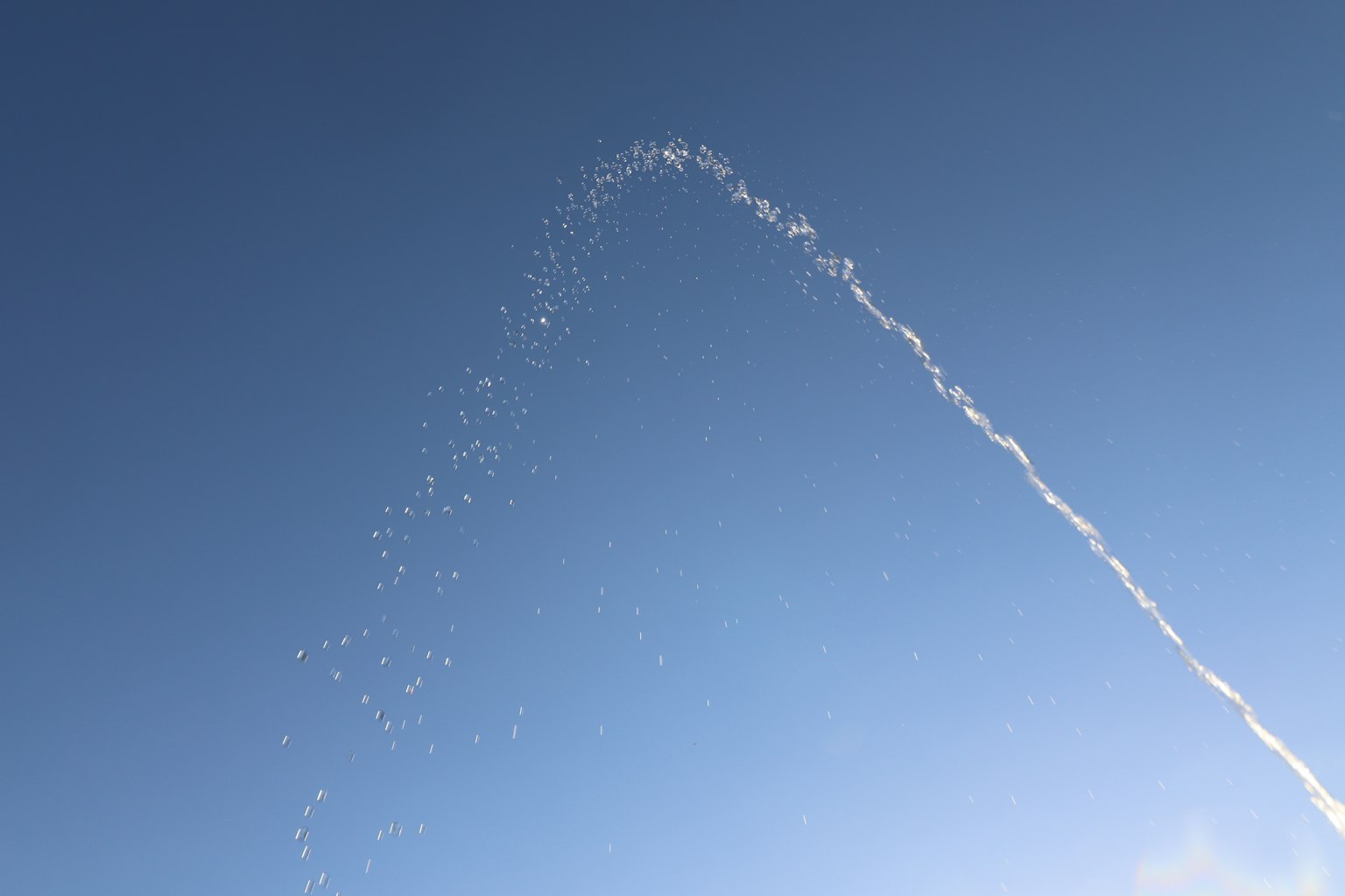 Air mancur membentuk lengkungan di langit biru