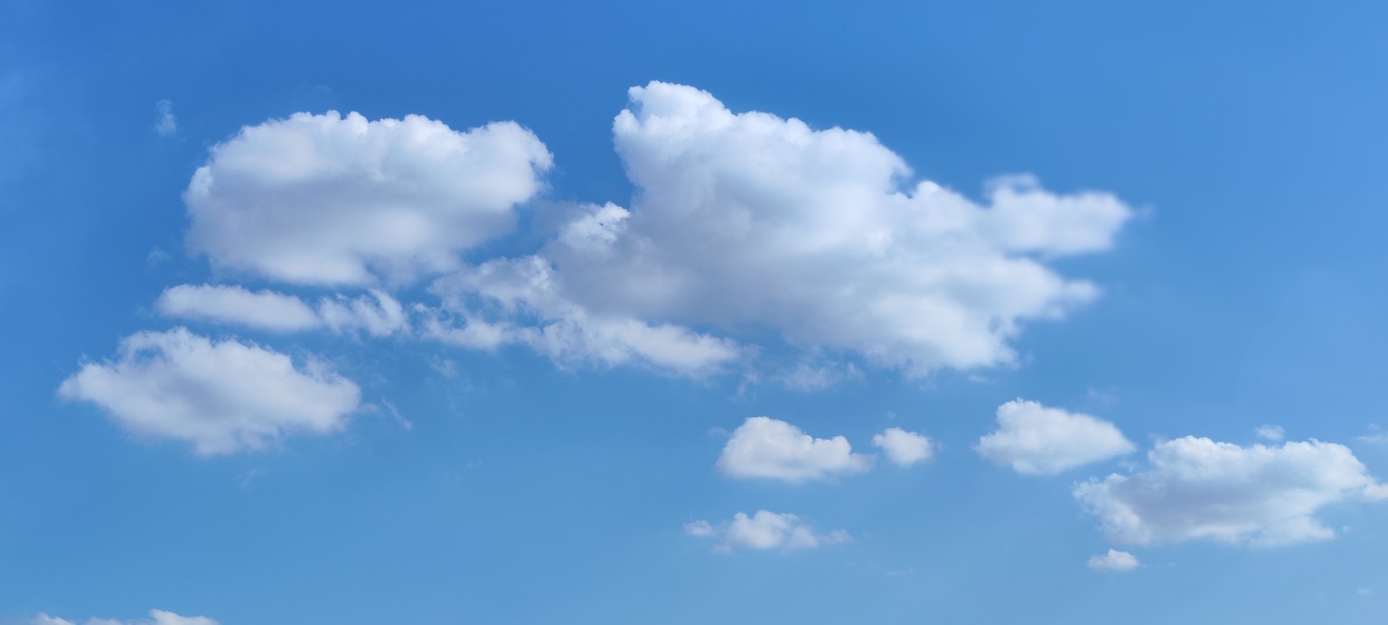 Awan putih berbulu tersebar di langit biru yang cerah