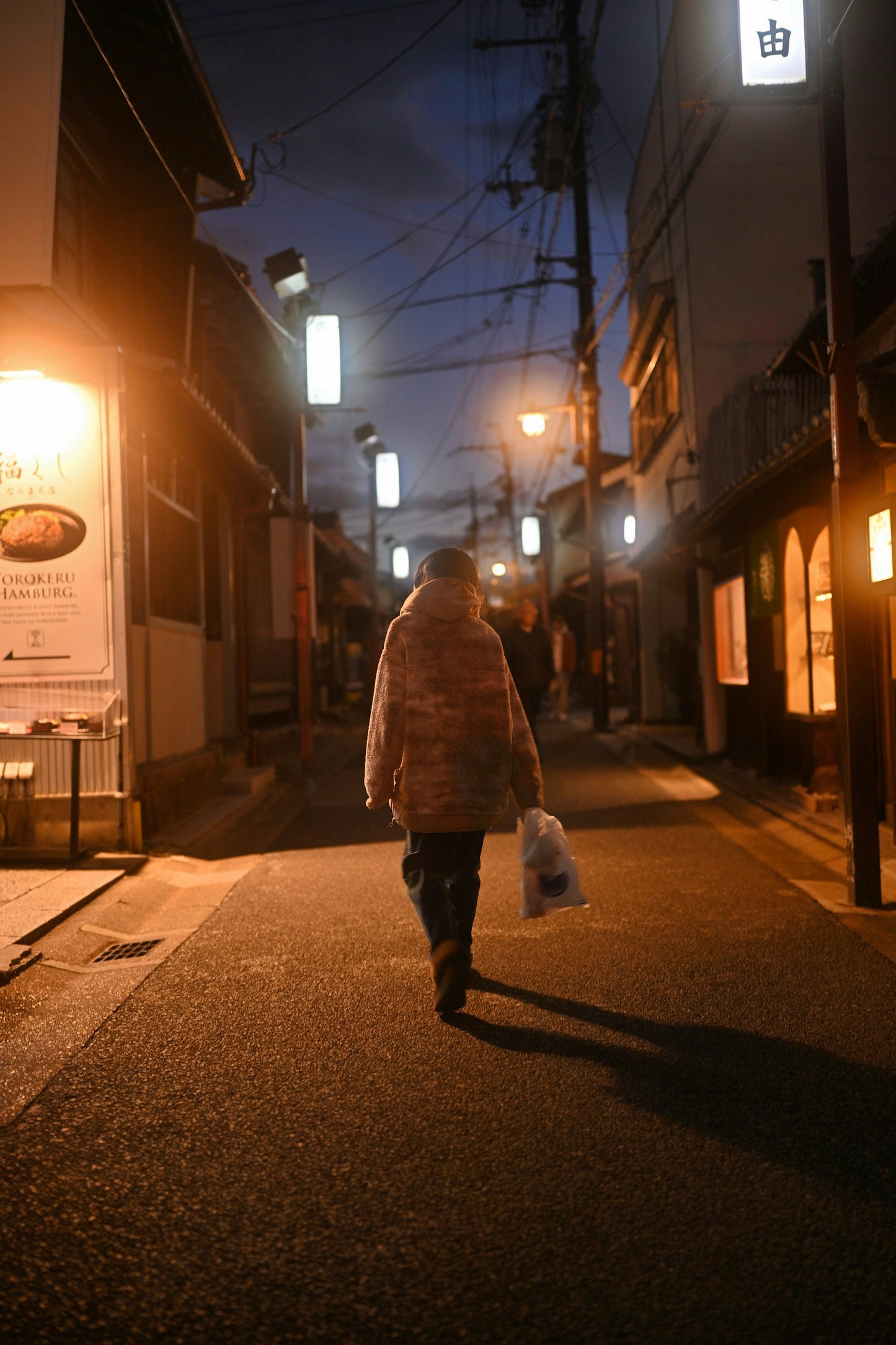 夜の路地を歩く人と提灯の灯りが並ぶ商店街の通り