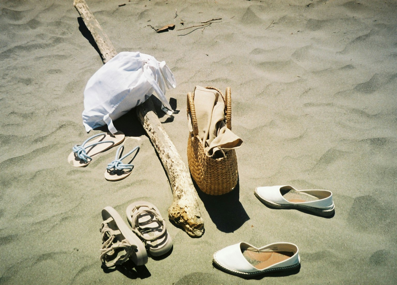 Weißes Hemd Sandalen Tasche Schuhe Treibholz am Sandstrand