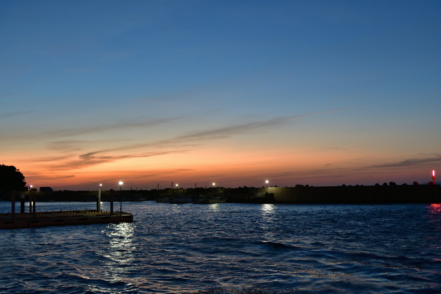 Tramonto sereno al fiume con luci che si riflettono sull'acqua