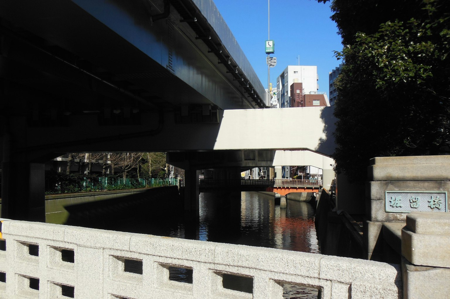 Vista de un puente elevado sobre un canal bajo un cielo azul claro con reflejos en el agua