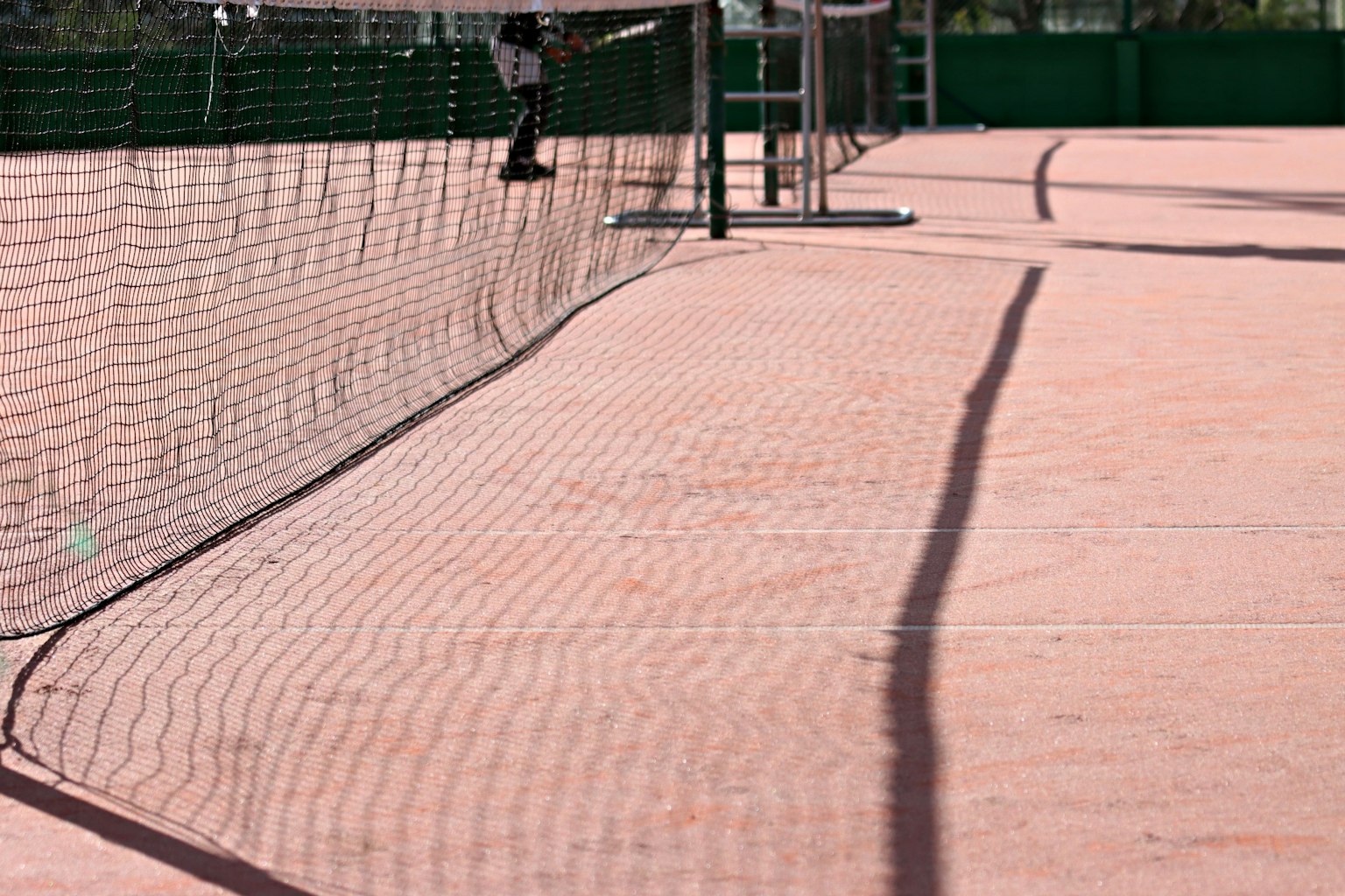 Gros plan sur un filet de tennis et une surface de jeu orange