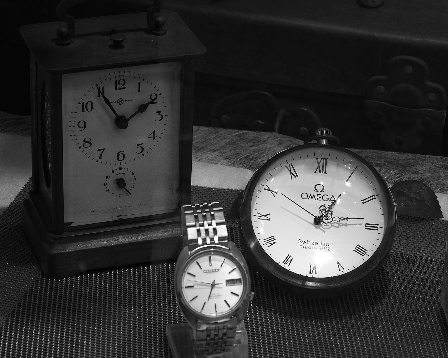 Tre orologi esposti in bianco e nero un orologio da camino antico e due orologi da polso