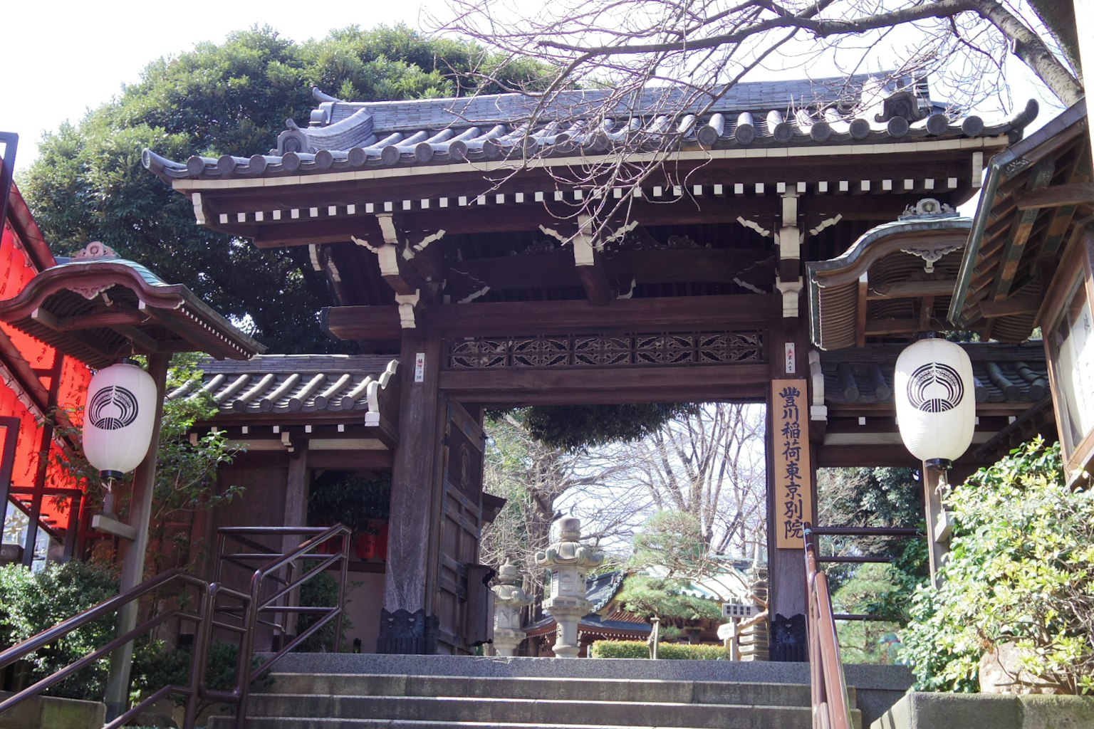 Traditional Japanese temple gate with surrounding lush greenery and lanterns