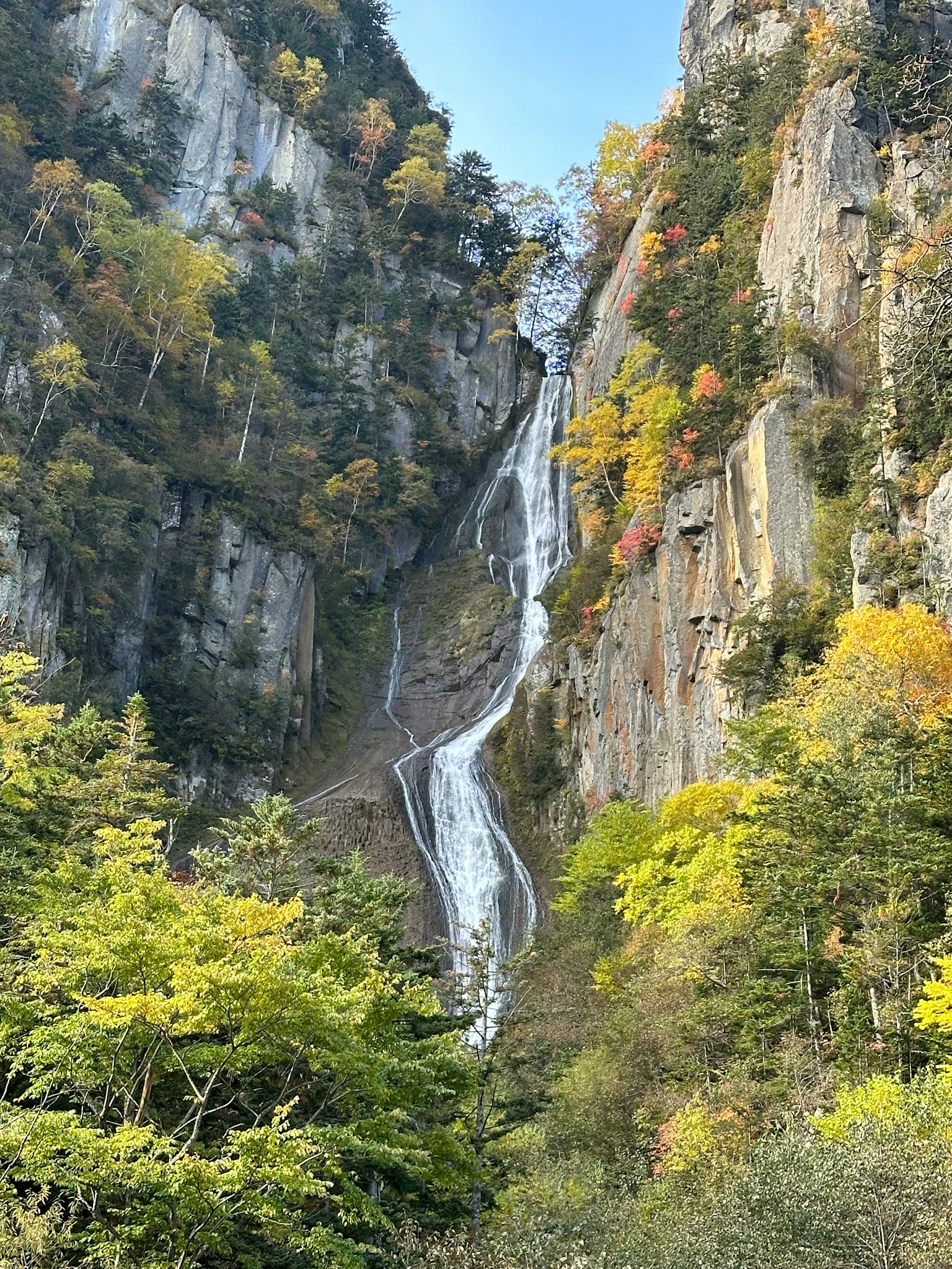 Mountain landscape with a waterfall cascading down surrounded by autumn foliage