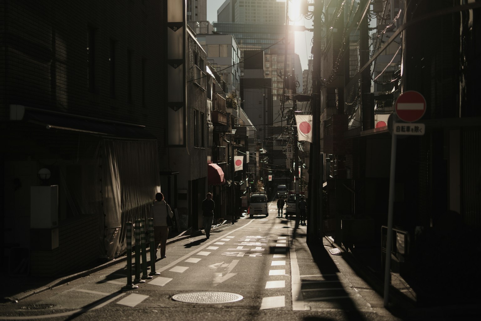 人們在東京一條狹窄的街道上散步，夕陽西下