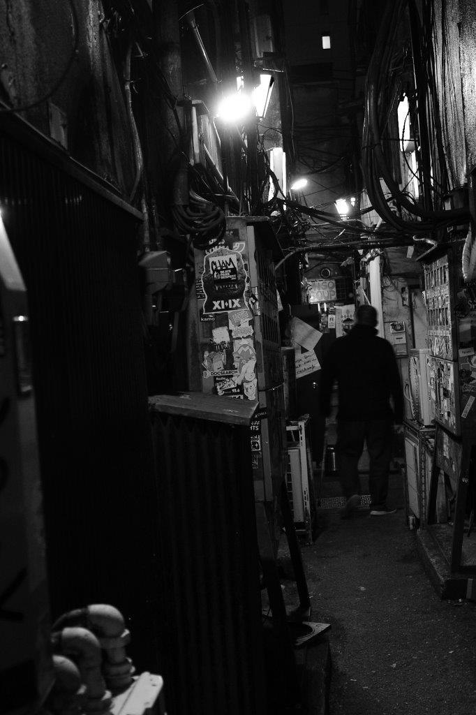 passage de ruelle sombre avec câbles suspendus et enseignes de boutiques