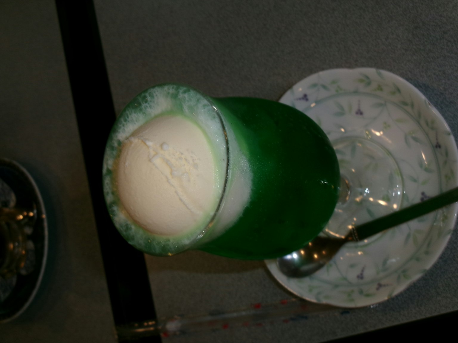Bebida verde coronada con una bola de helado servida en un vaso