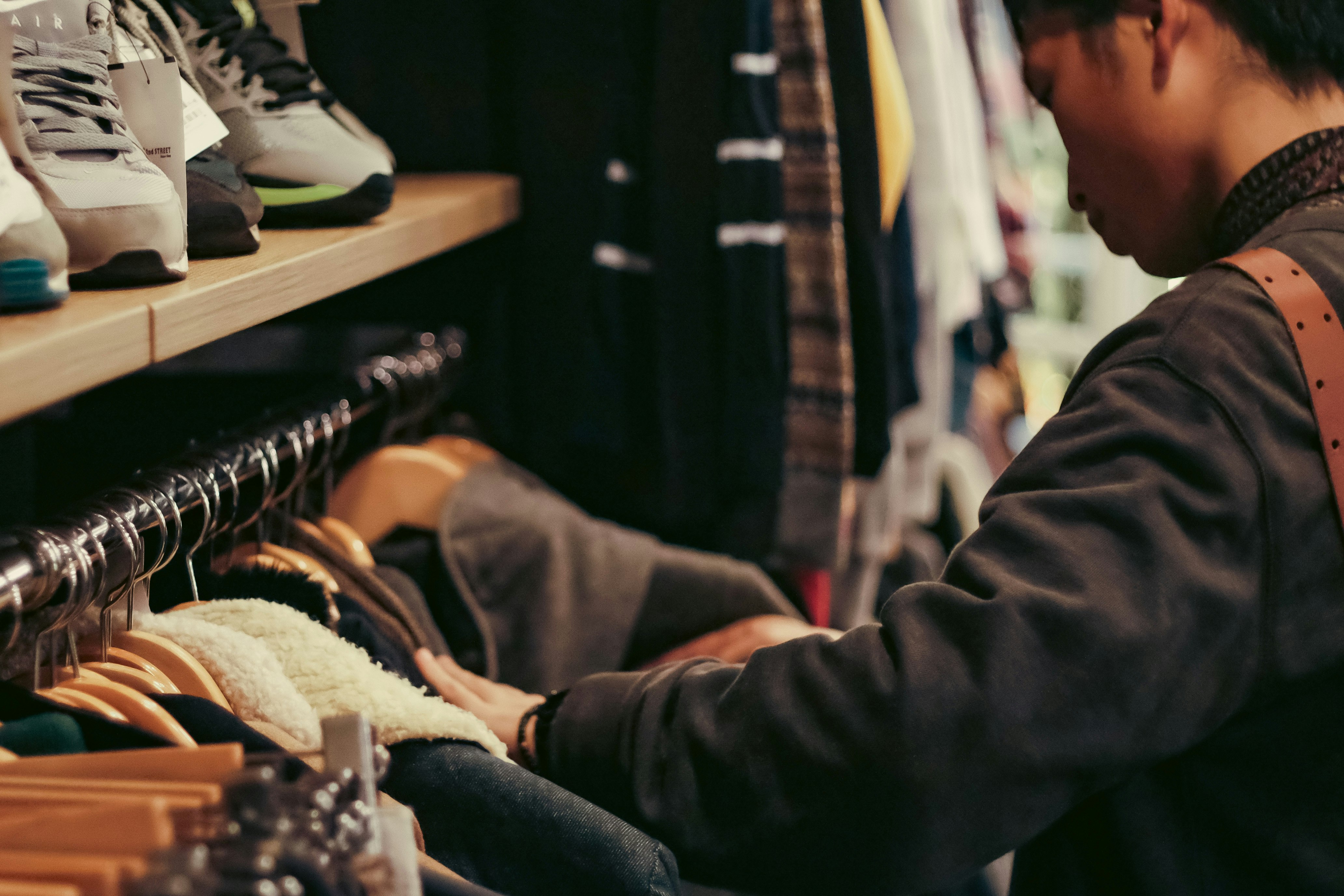 person trying on clothes beside a rack in a shop