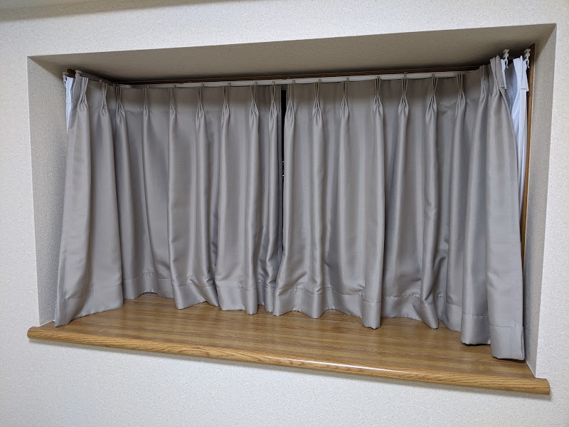 木製の棚の上に掛かった白いカーテン