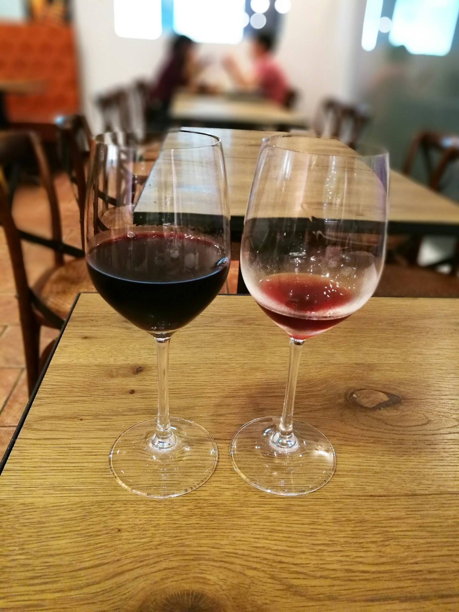 Una scena con un bicchiere di vino rosso e un bicchiere di vino rosato su un tavolo di legno
