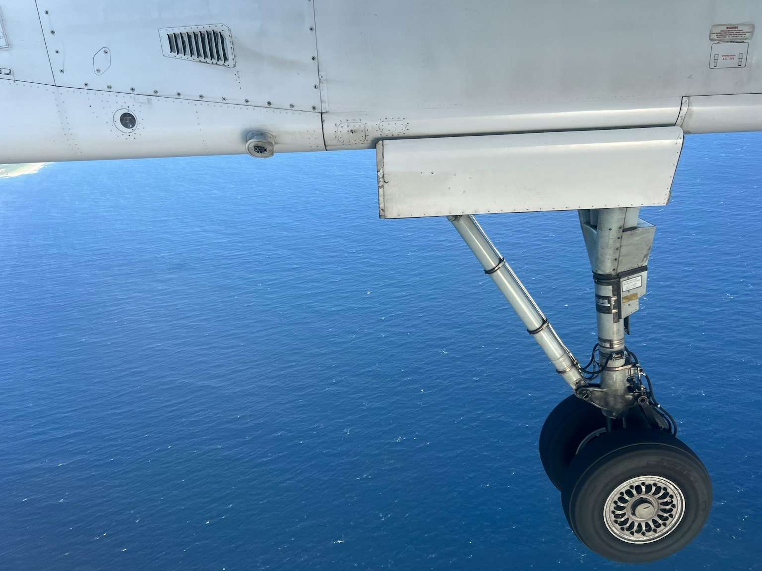 Nahaufnahme eines Flugzeugfahrwerks über dem Ozean