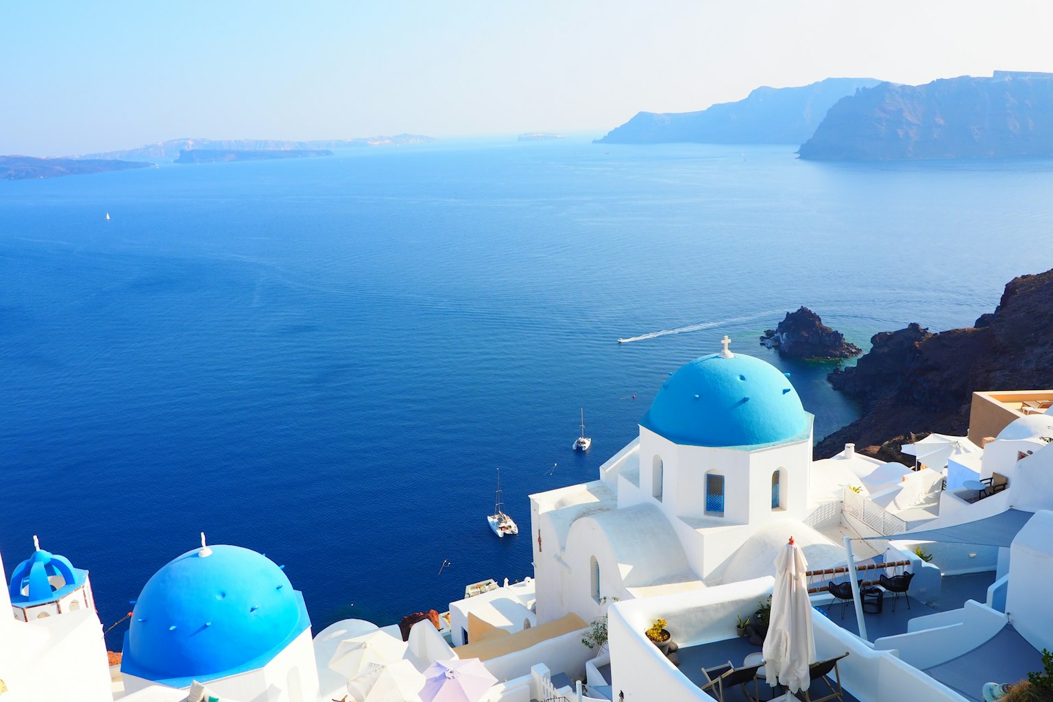 Cảnh Santorini với mái vòm xanh và tòa nhà trắng nhìn ra biển