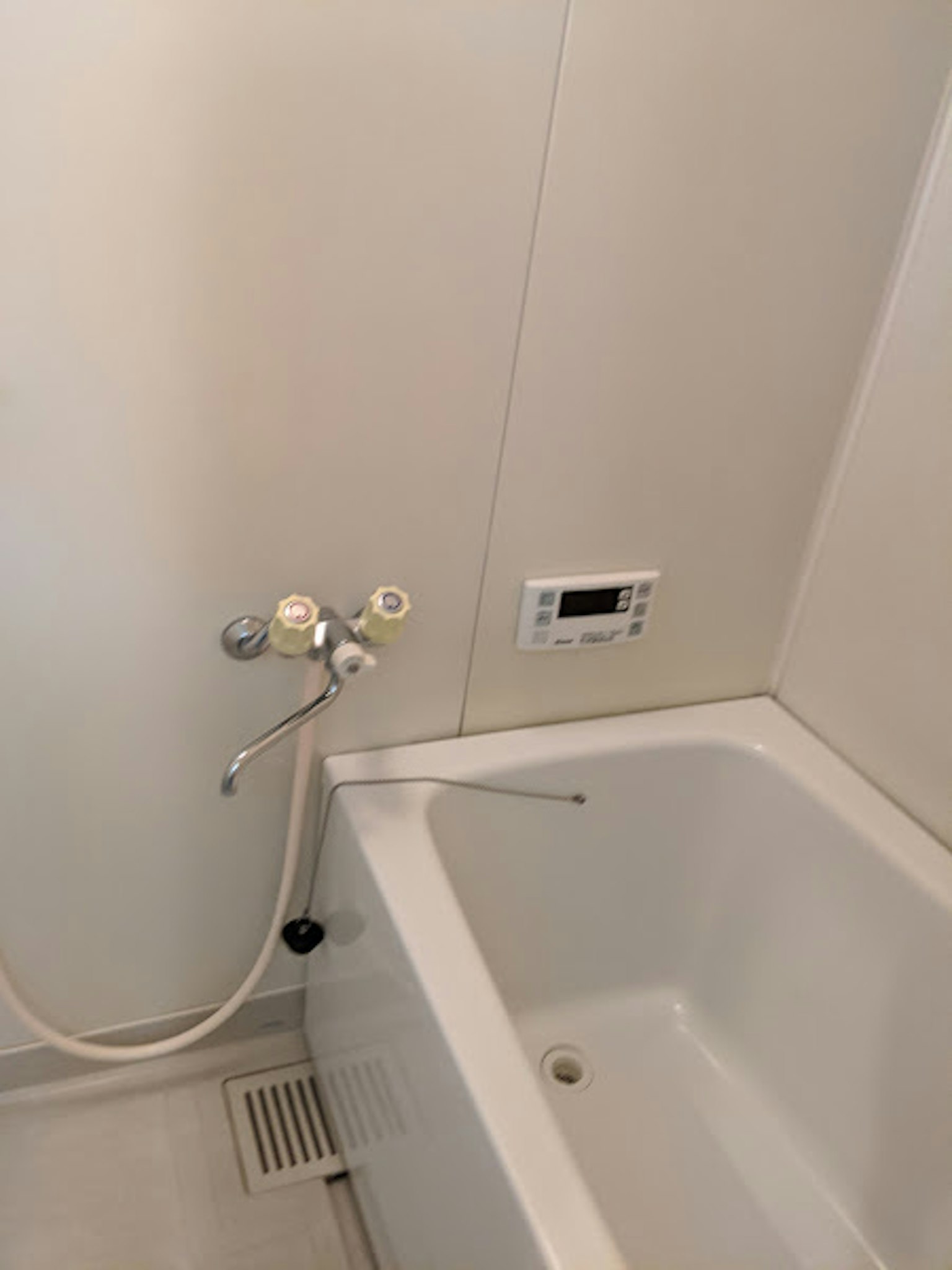 Ein Teil eines Badezimmers mit einer weißen Badewanne und Duscharmaturen