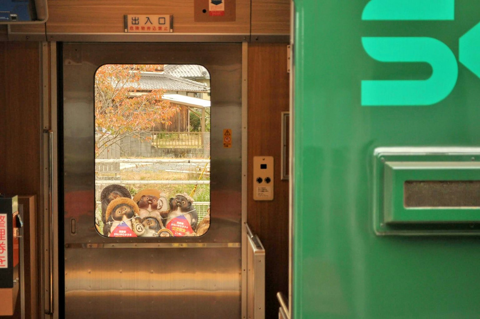 Vue depuis une porte de train montrant des gens dehors