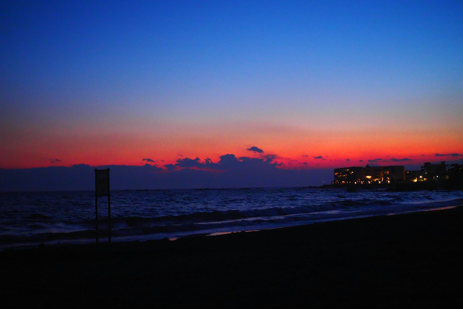 海灘場景，藍天與橙色夕陽在海面上反射
