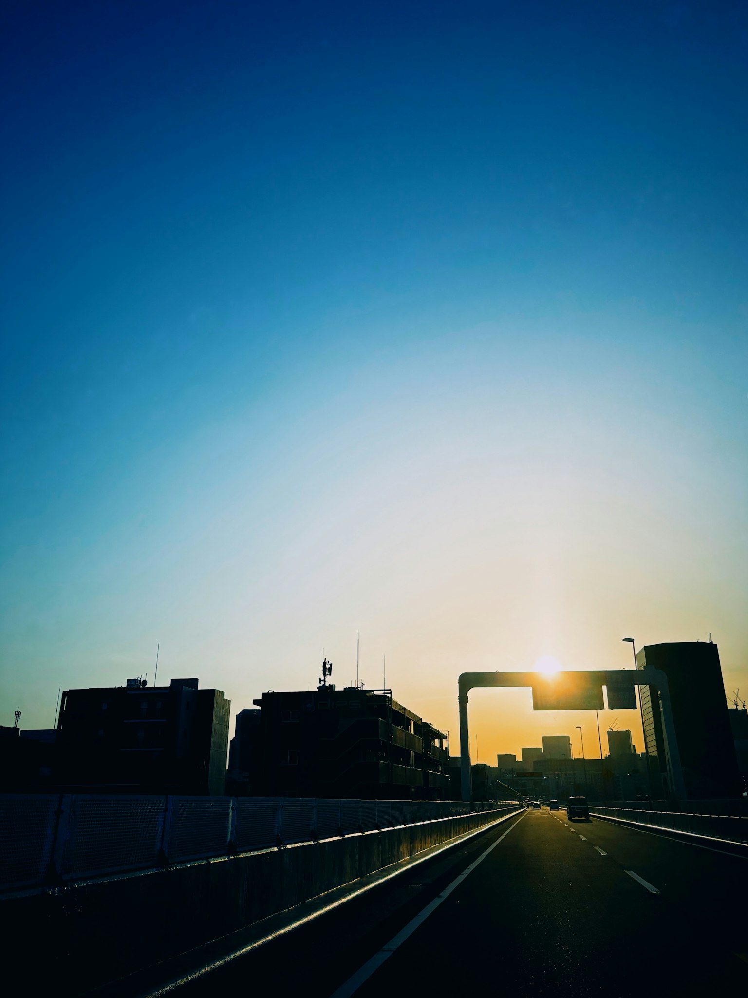 Stadtansicht bei Sonnenuntergang mit Silhouette von Autobahn und blauem Himmel