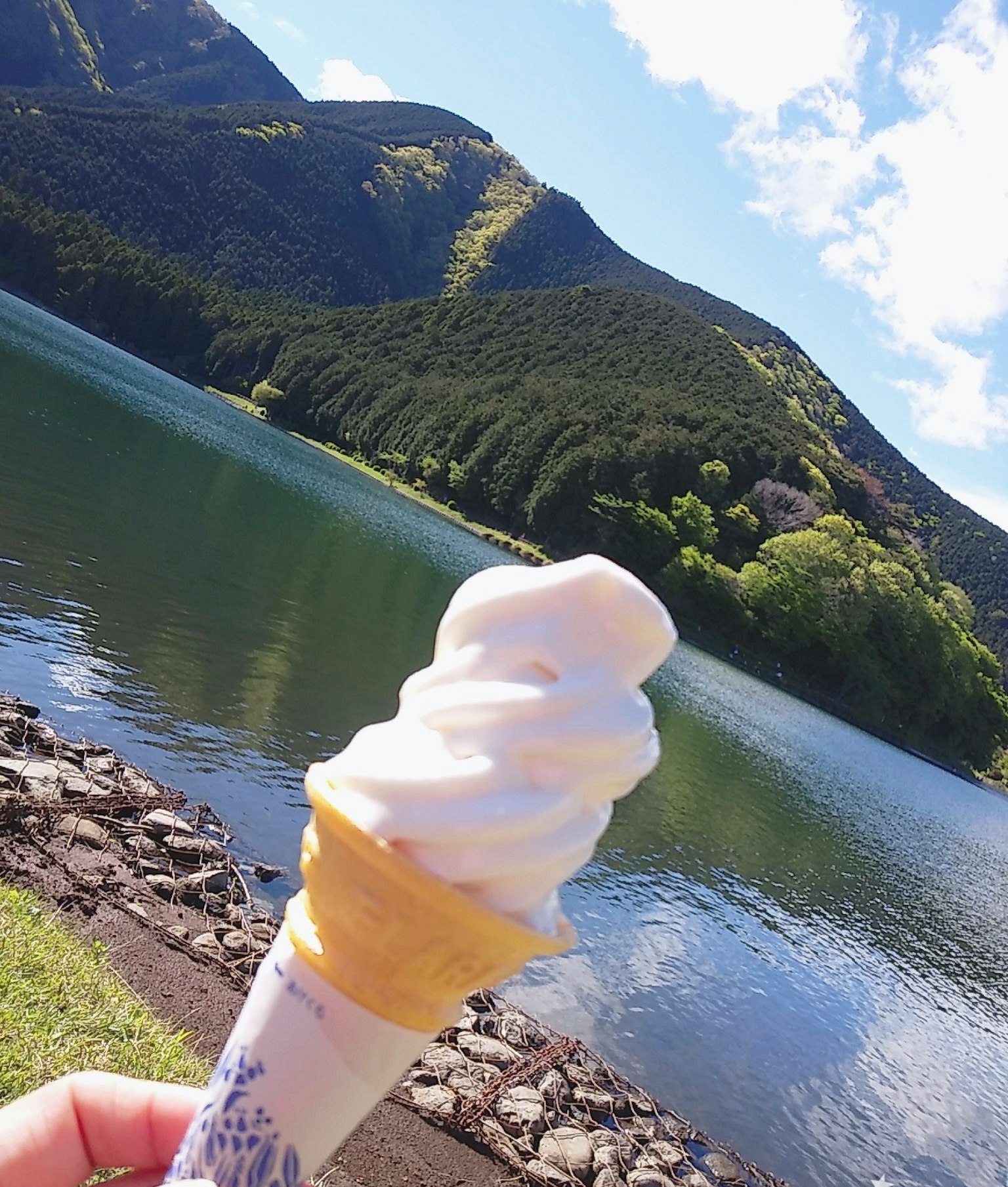 手持软冰淇淋，背景是湖泊和山脉