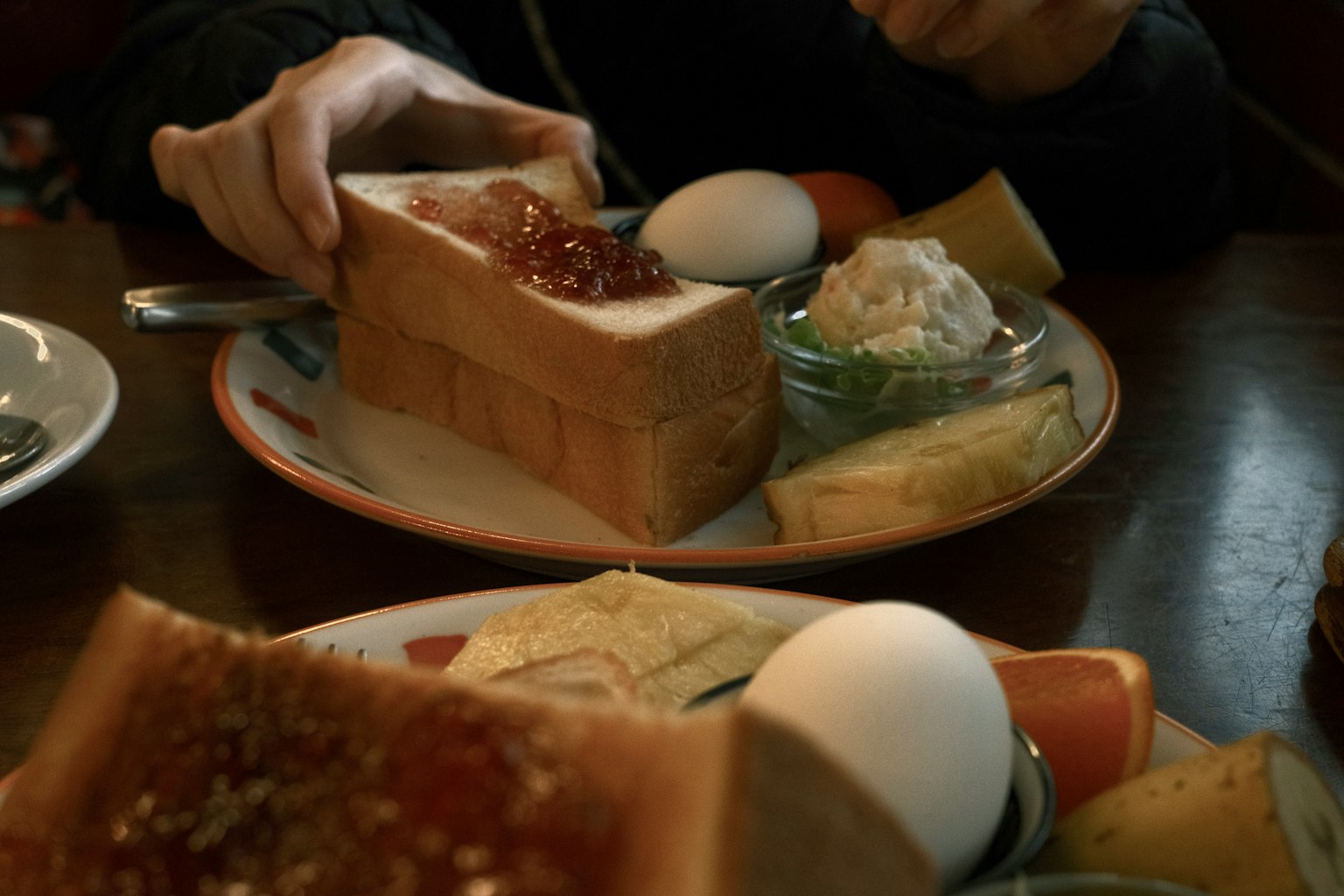 Adegan sarapan dengan tangan memegang roti panggang dan berbagai hidangan sampingan