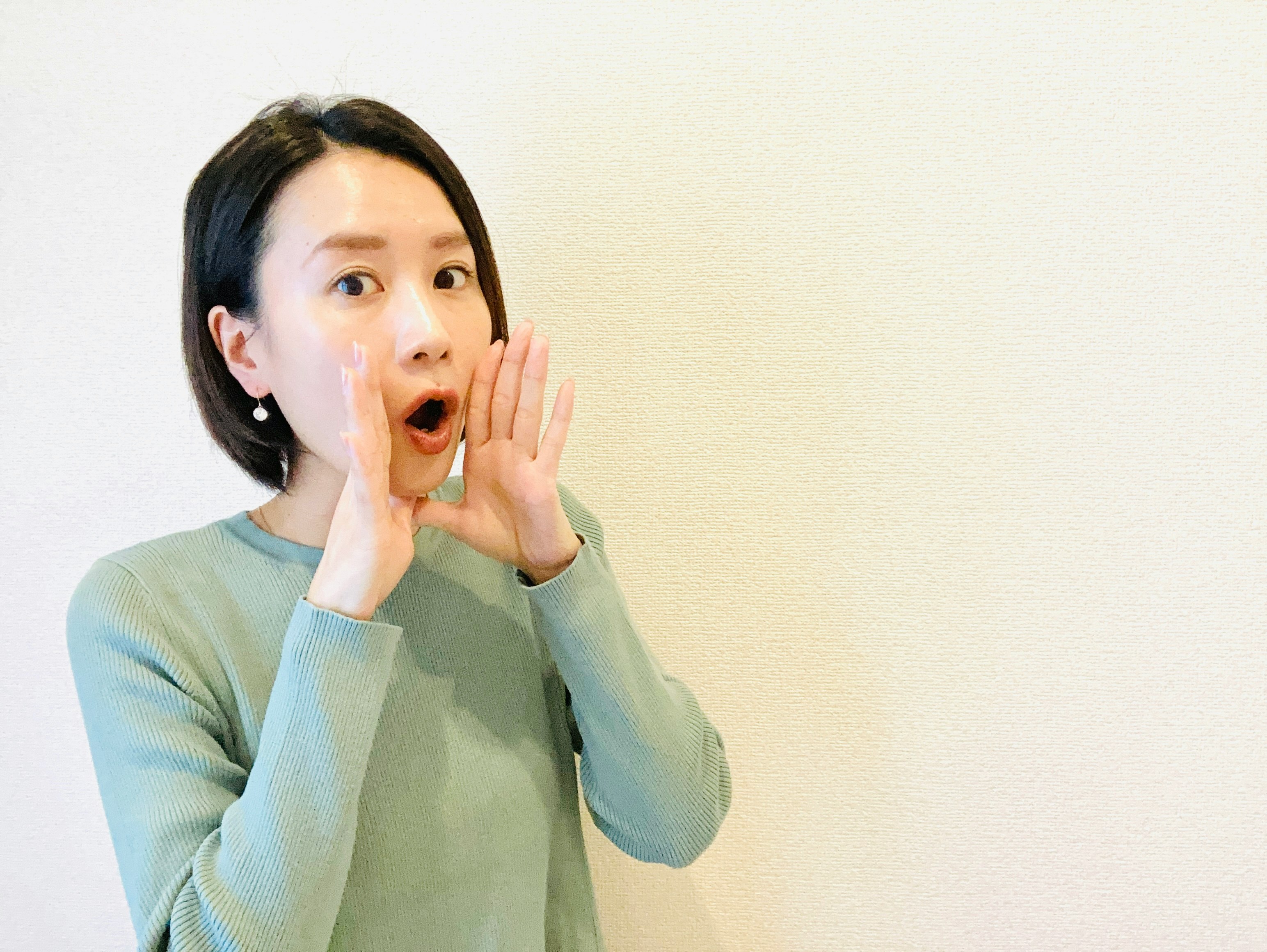 驚いた表情の女性が手で口元を押さえるポーズ