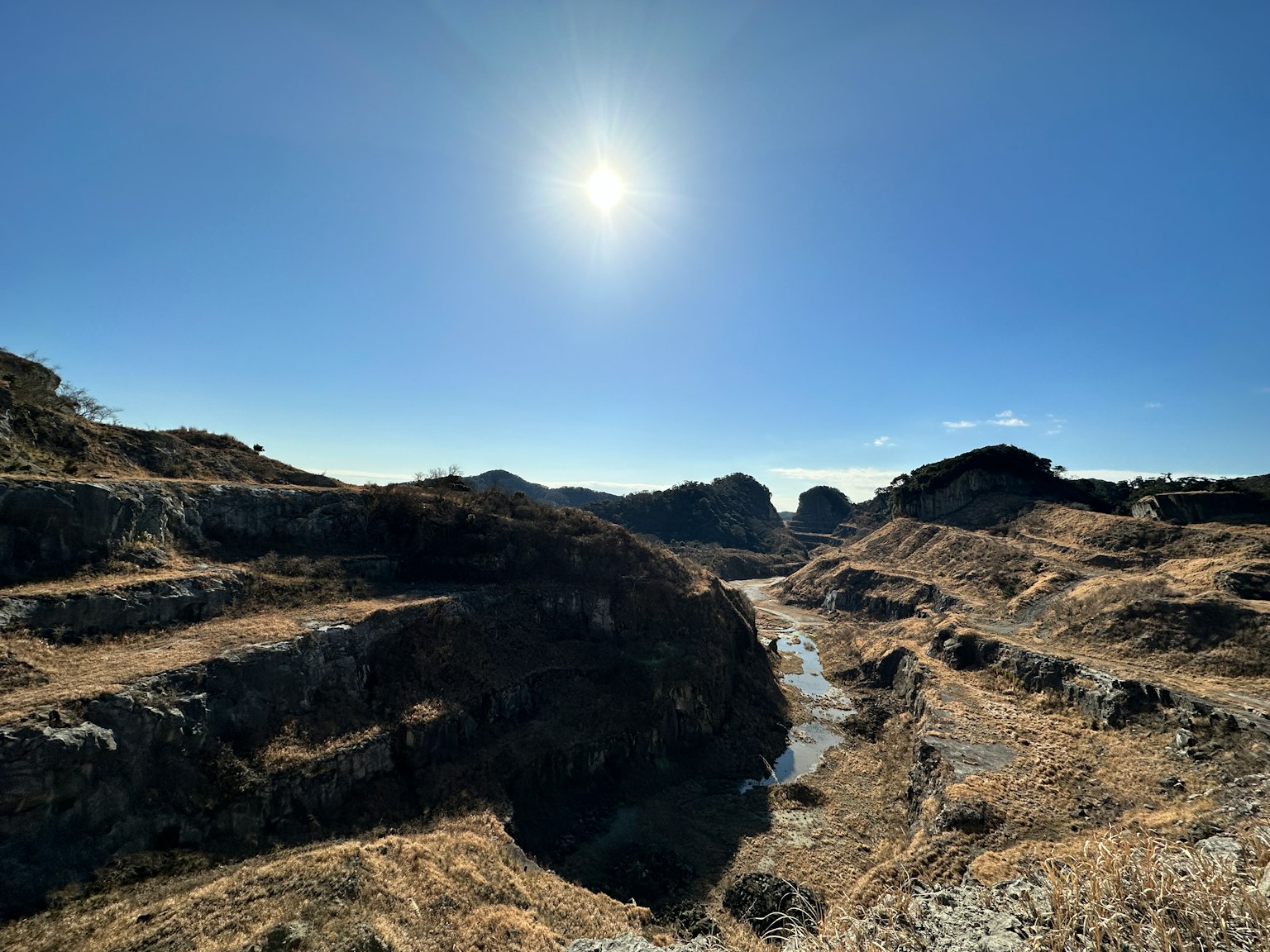 Dry canyon landscape with rocky formations under bright sunlight