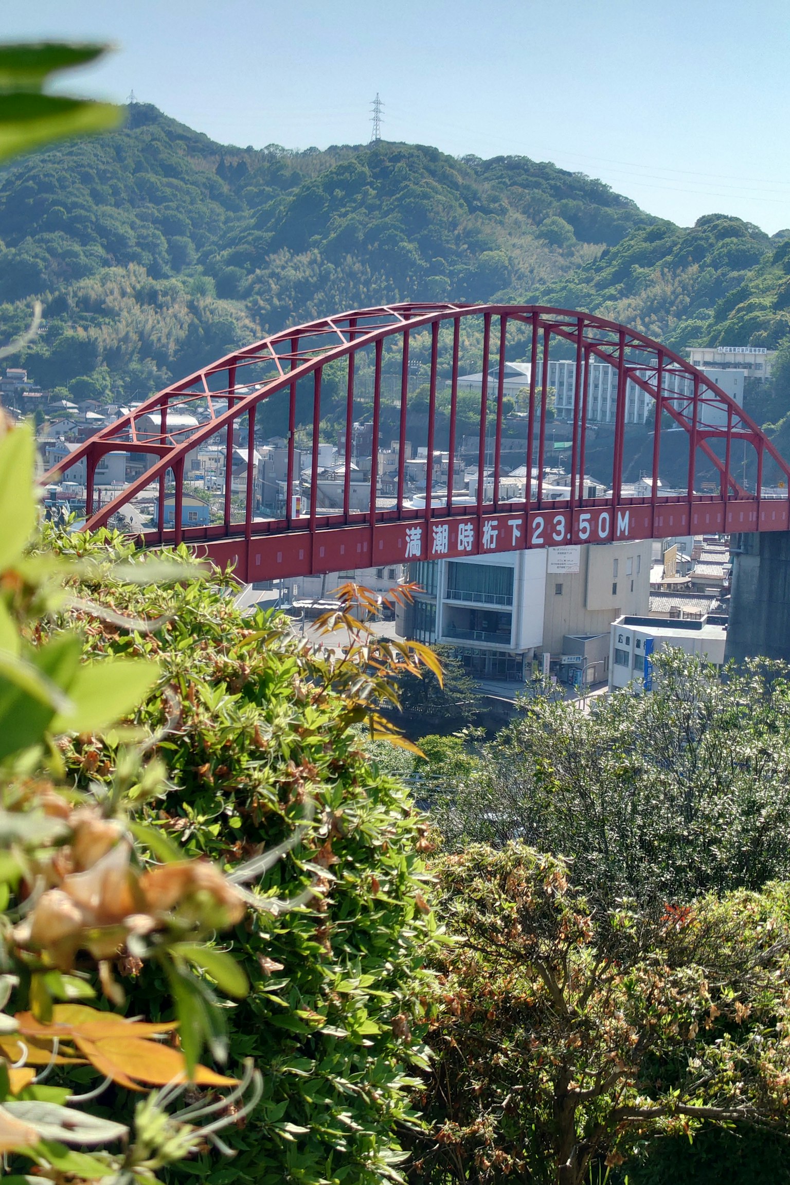 Ponte ad arco rosso con colline circostanti e vista sulla città
