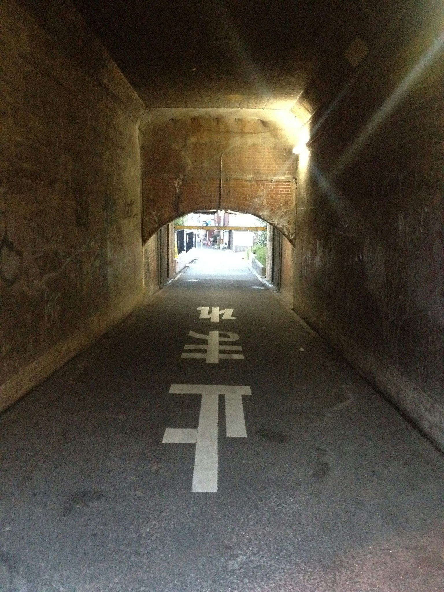 Vue d'un tunnel avec lumière au bout et marquages routiers