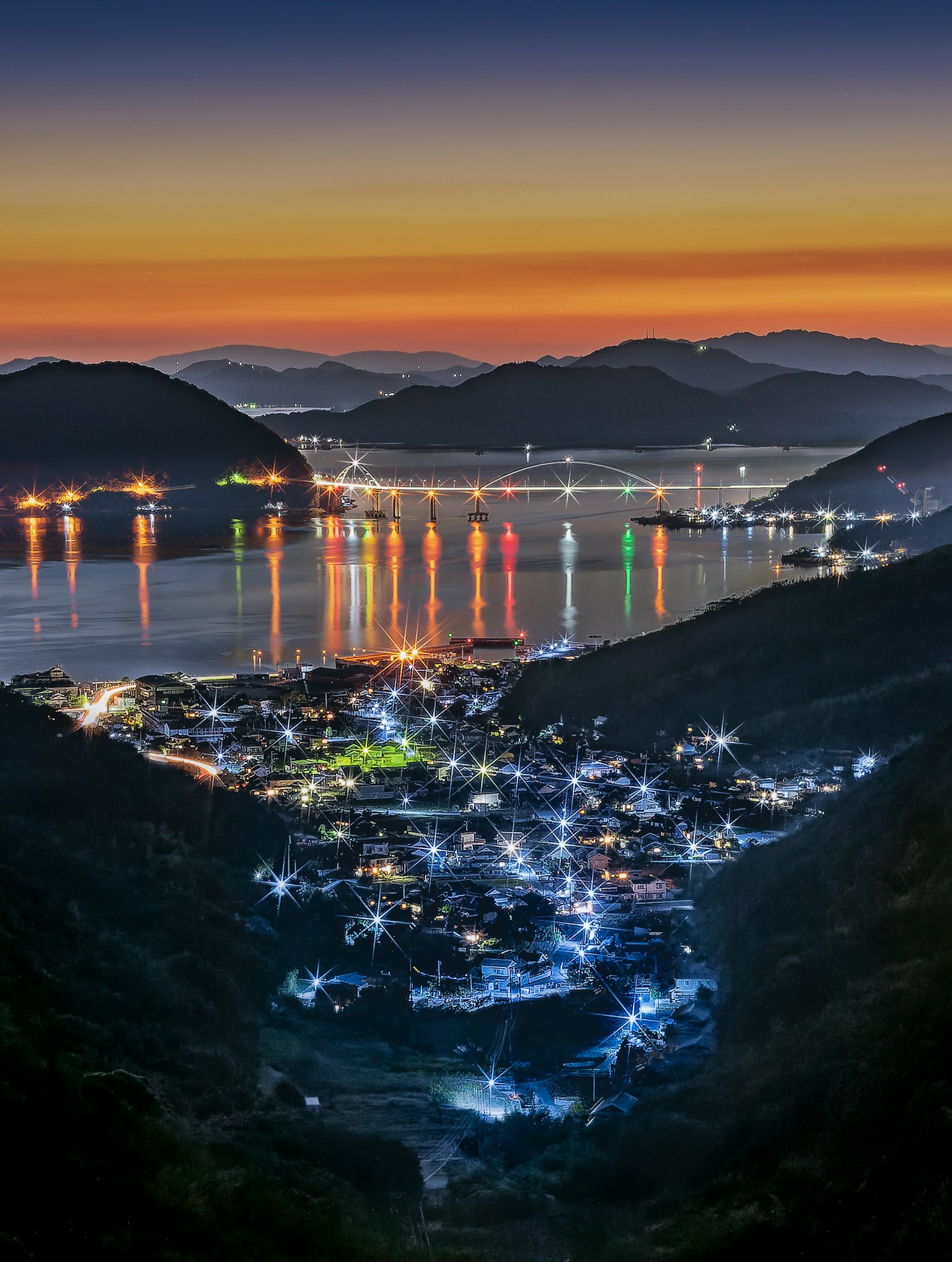 黄昏时分海滨小镇的风景，五光十色的灯光映照在水面上